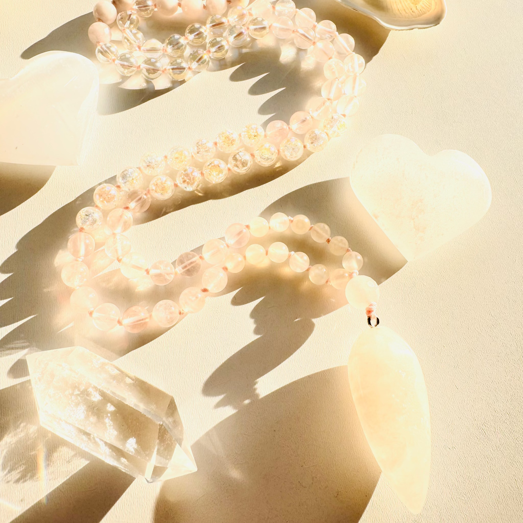 Pearl bracelets on a sandy surface with seashells