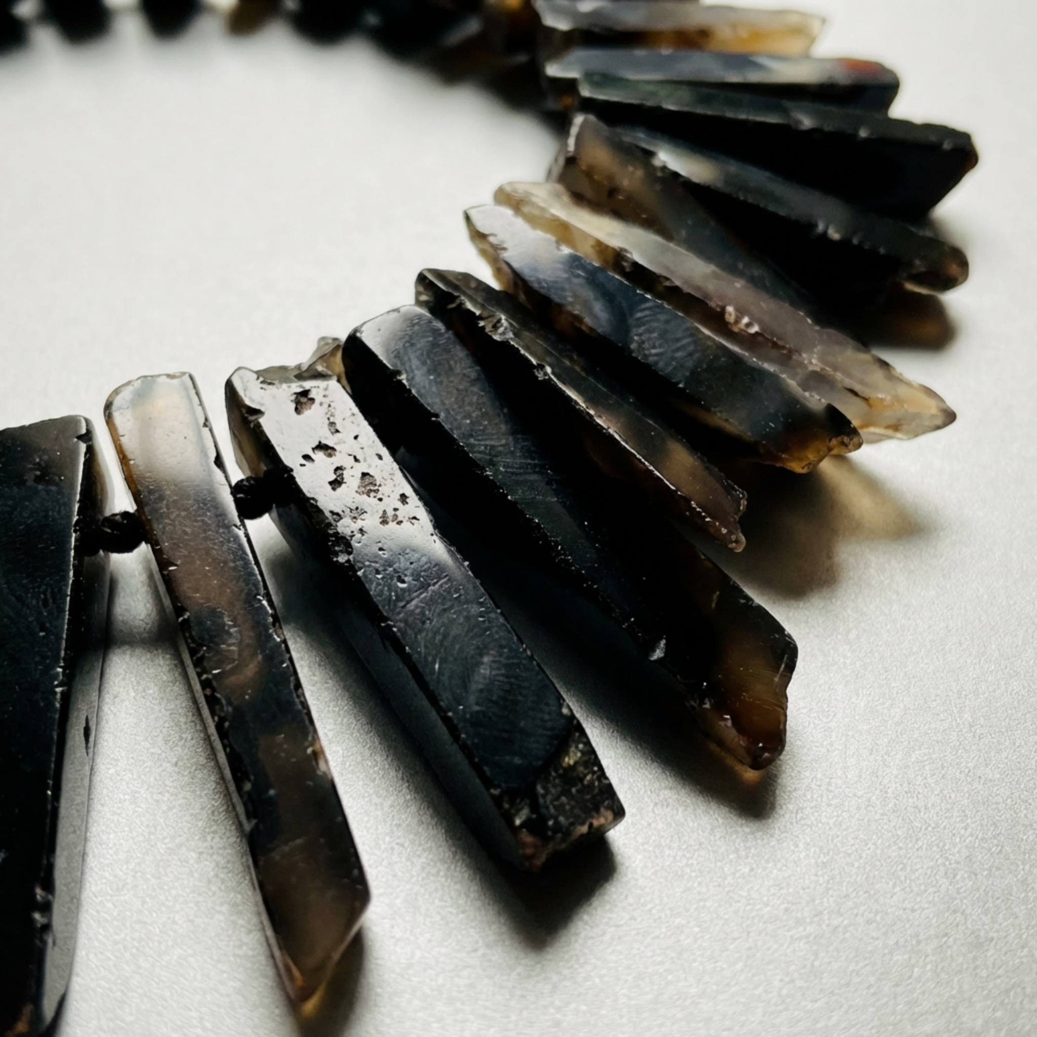 Necklace with dark, agate stone beads on a light background