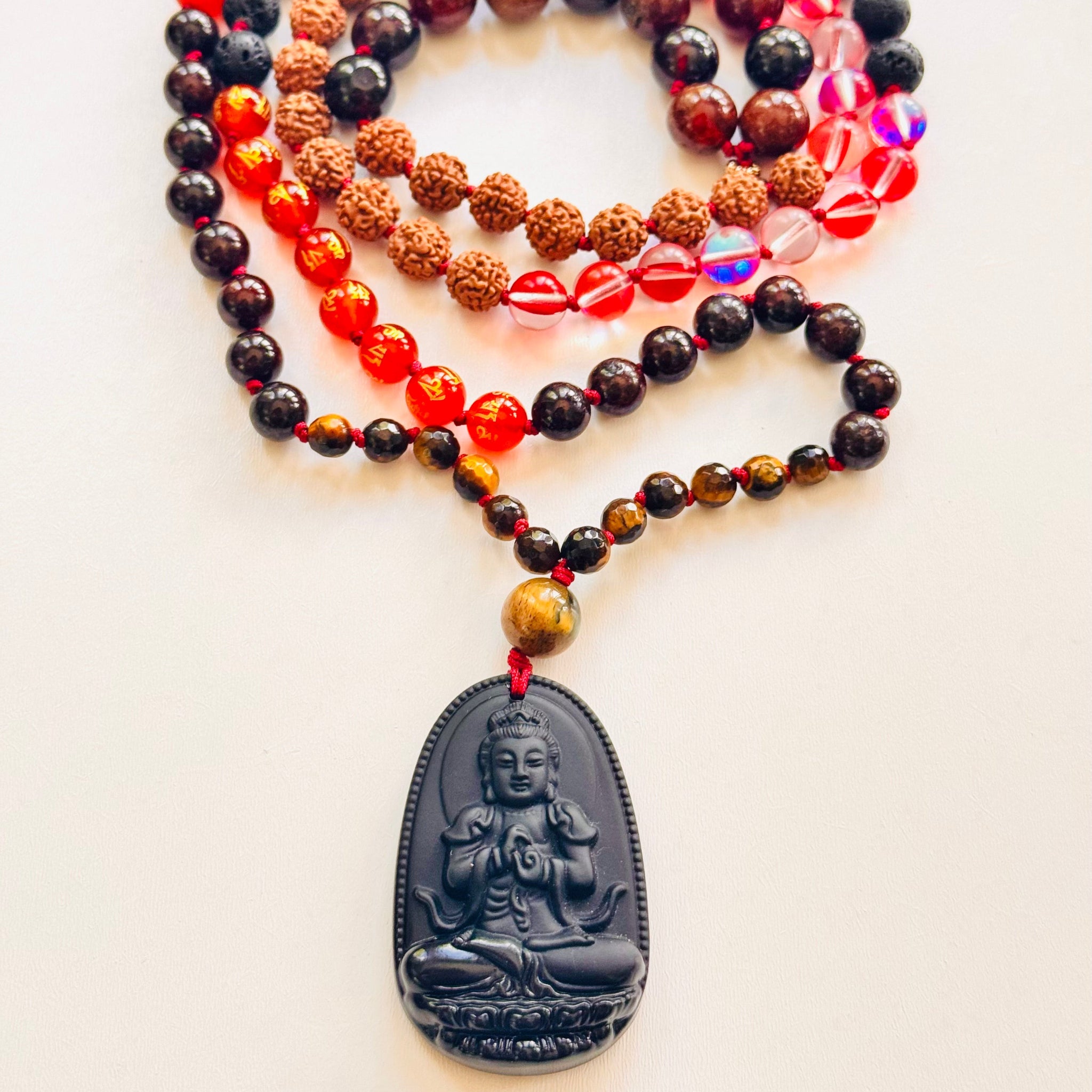 Necklace with Buddha pendant and colorful beads on a white background with crystals and a feather.