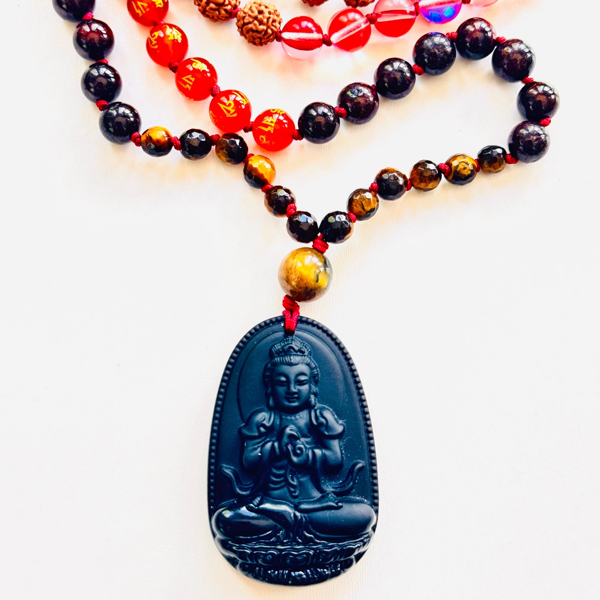 Necklace with multicolored beads and a black Buddha pendant on a white background
