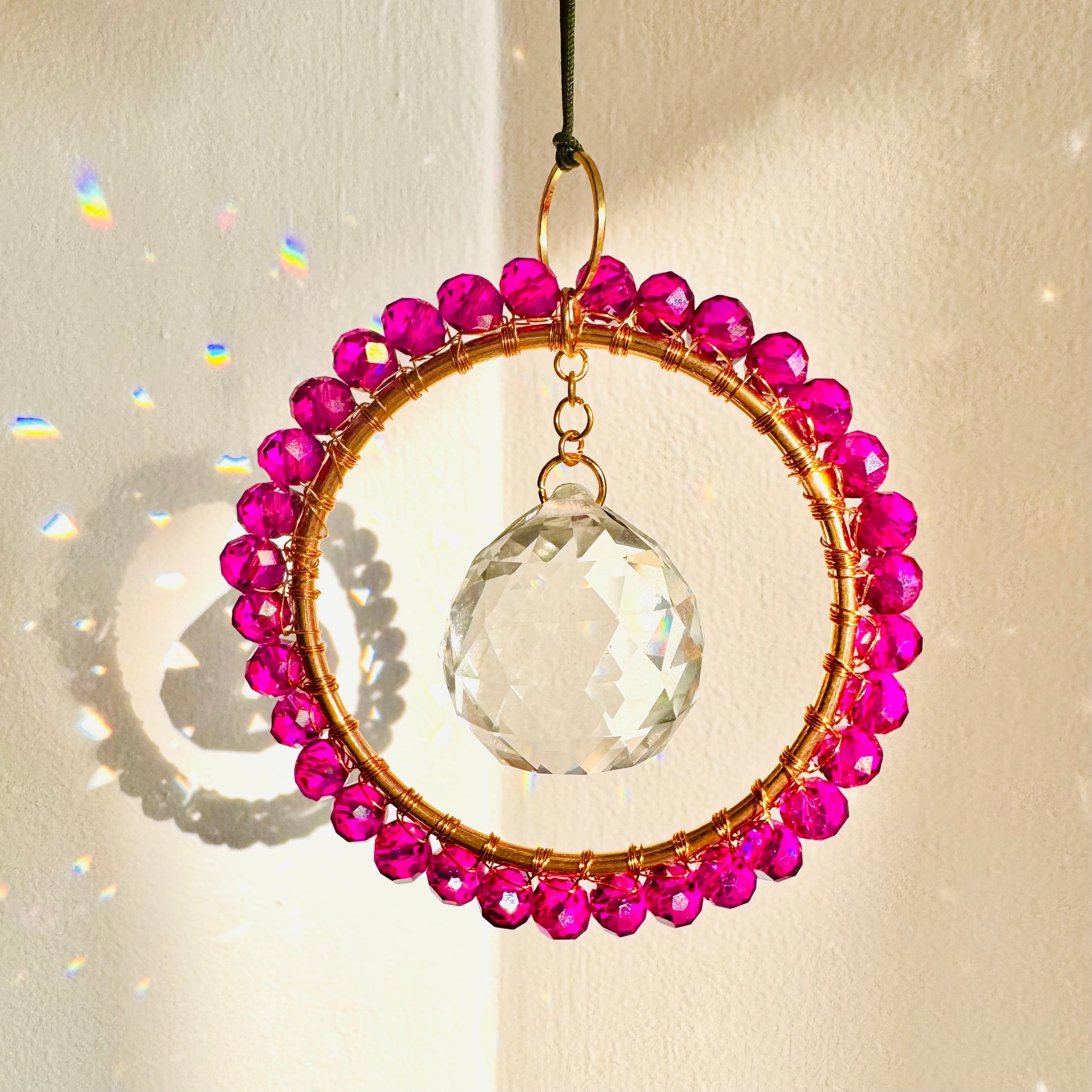 Crystal hanging ornament with pink beads on a beige background