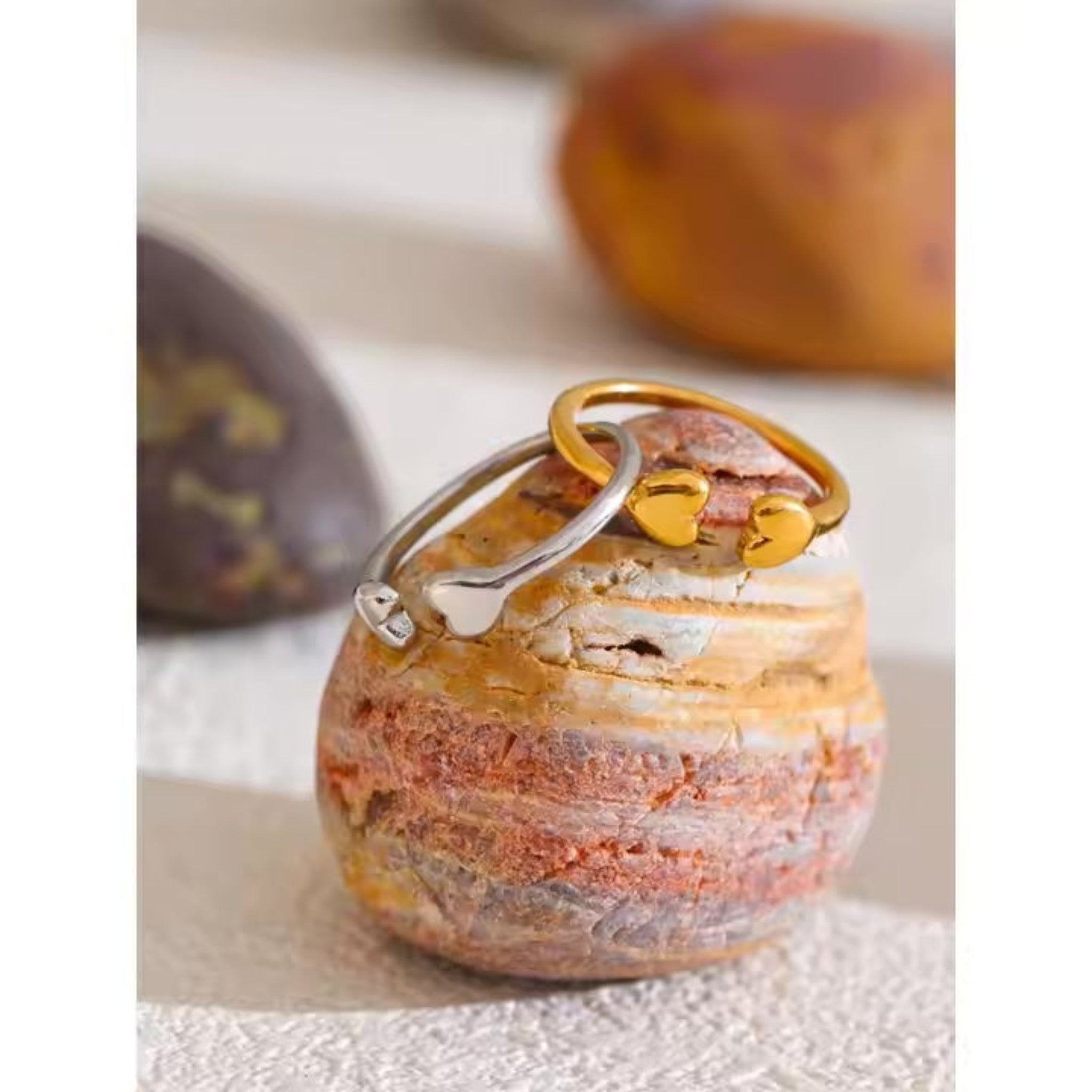 Silver ring with gold accents on a textured stone surface.