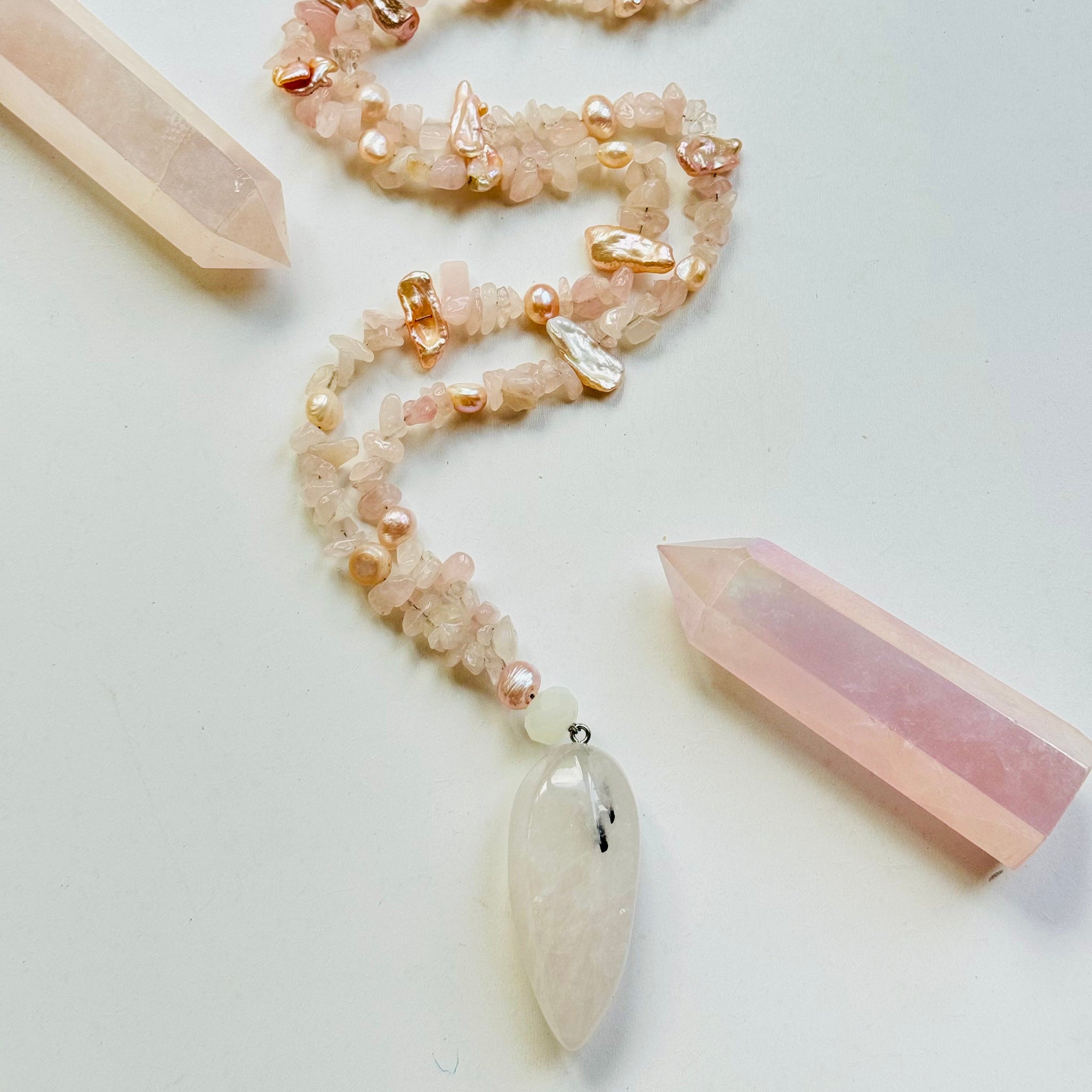 A Divine Love Necklace with a Clear Quartz pendant, featuring Rose Quartz and Nacre (Mother of Pearl) beads, and a single Clear Quartz teardrop-shaped pendant.