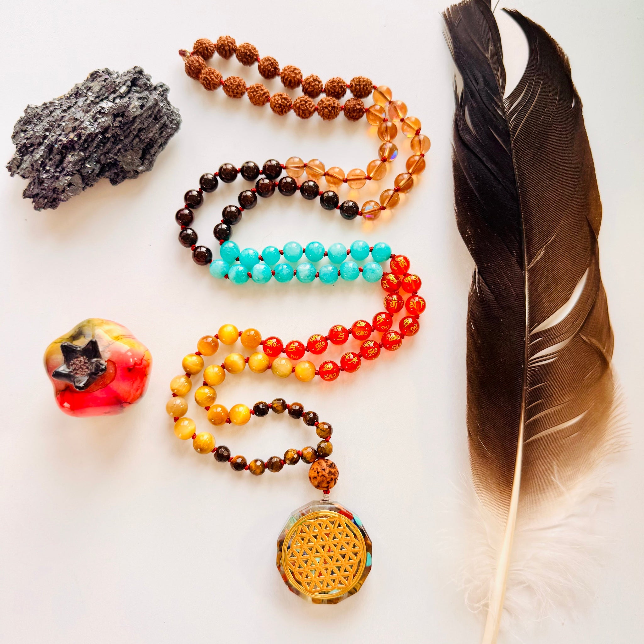 Colorful beaded necklaces with a feather and crystal on a white background