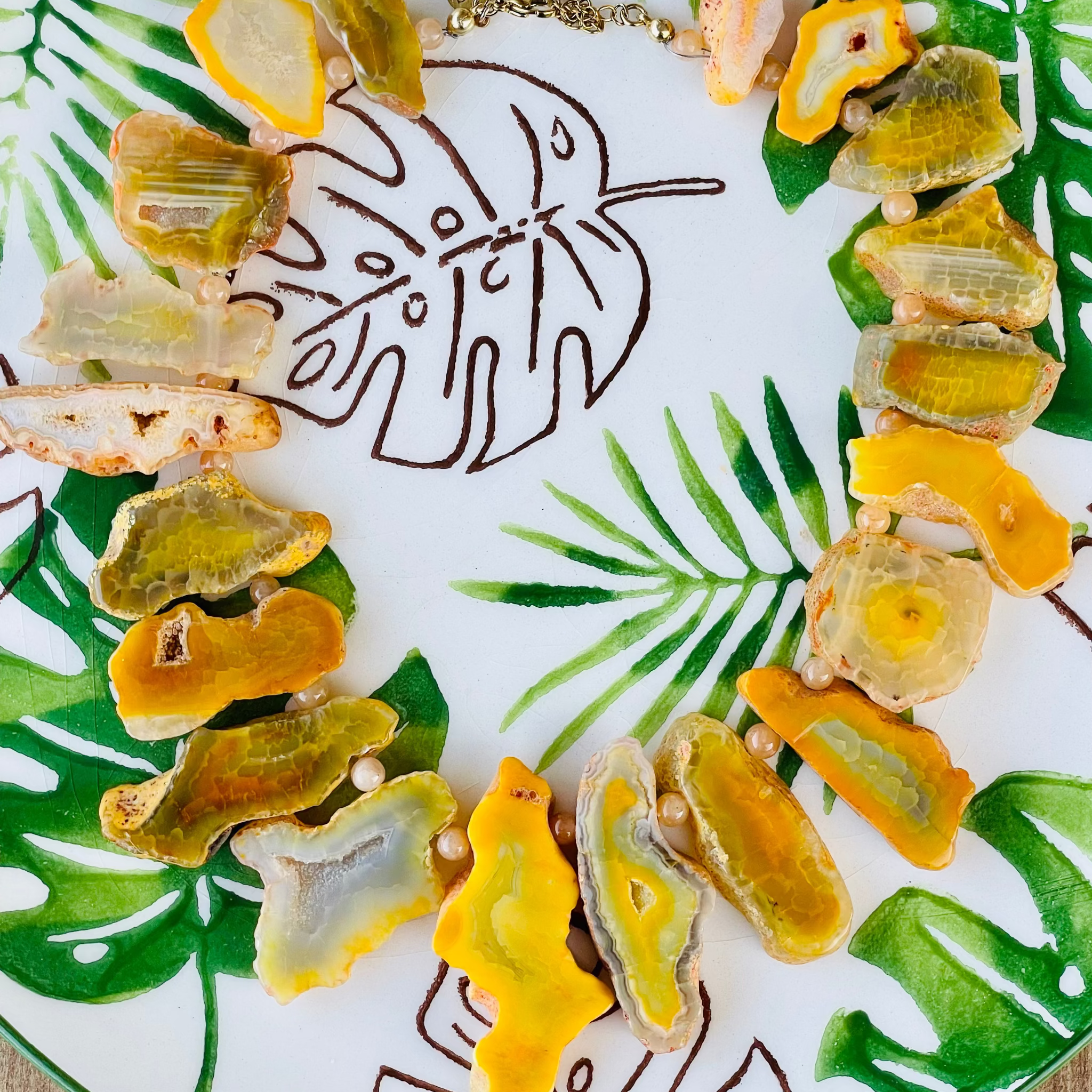 Decorative plate with leaf design and yellow and green food items on a wooden surface