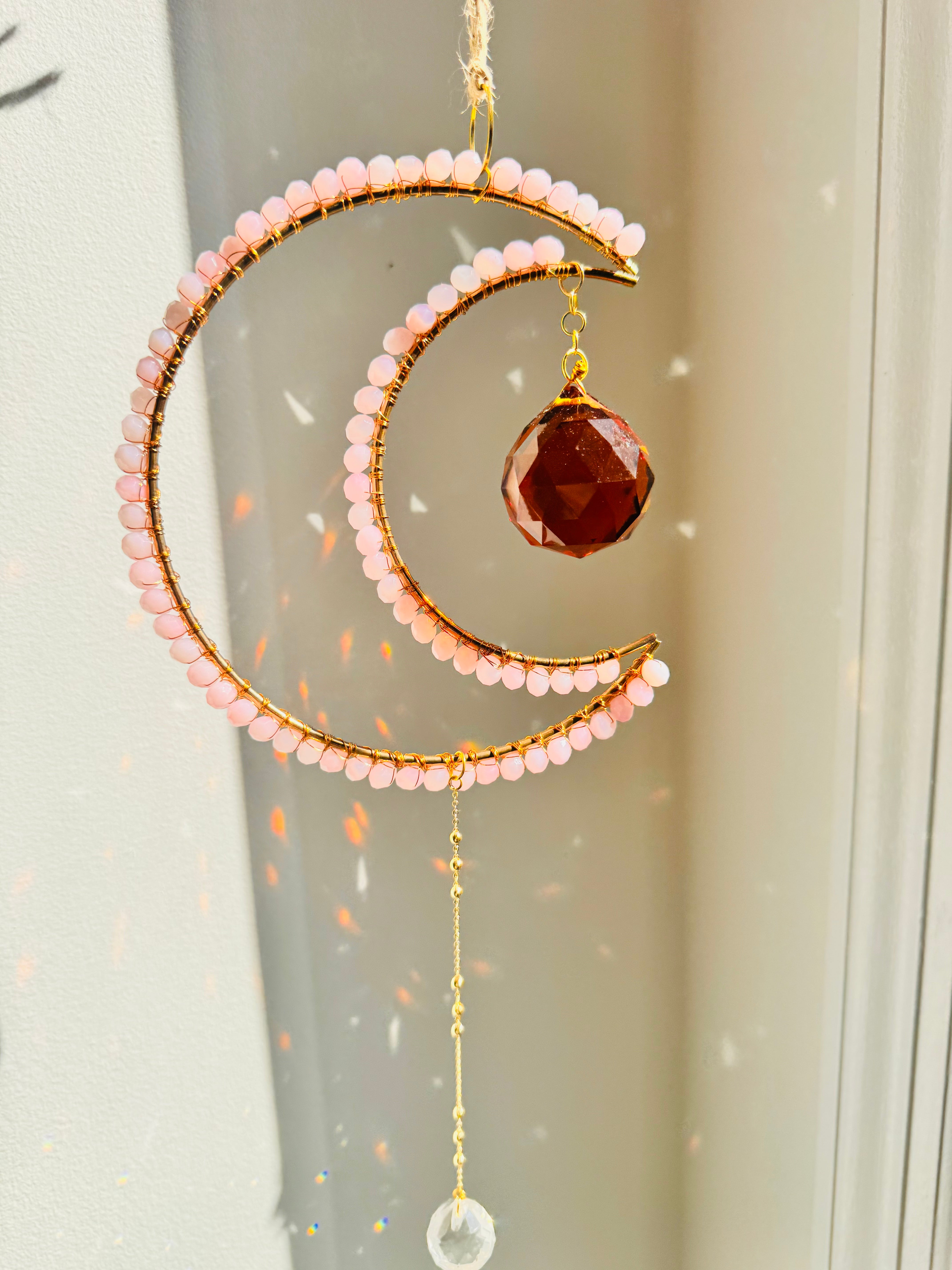 Decorative hanging ornament with pink beads and a brown gemstone on a neutral background