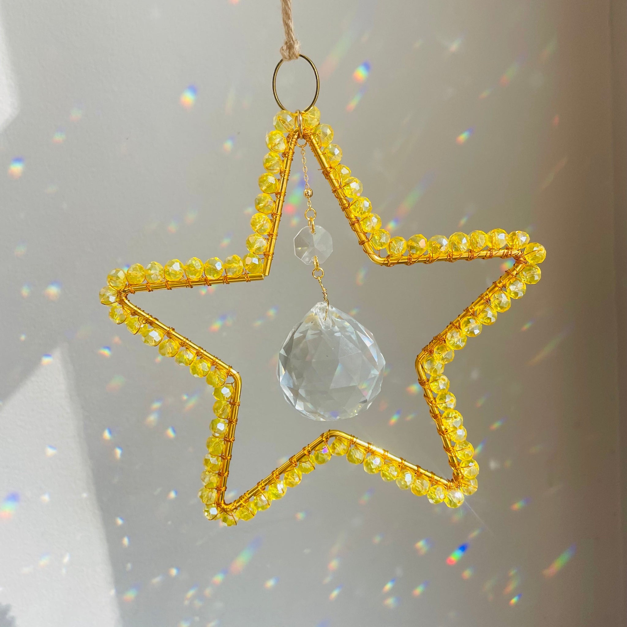 Star-shaped ornament with yellow beads and a clear crystal on a light gray background