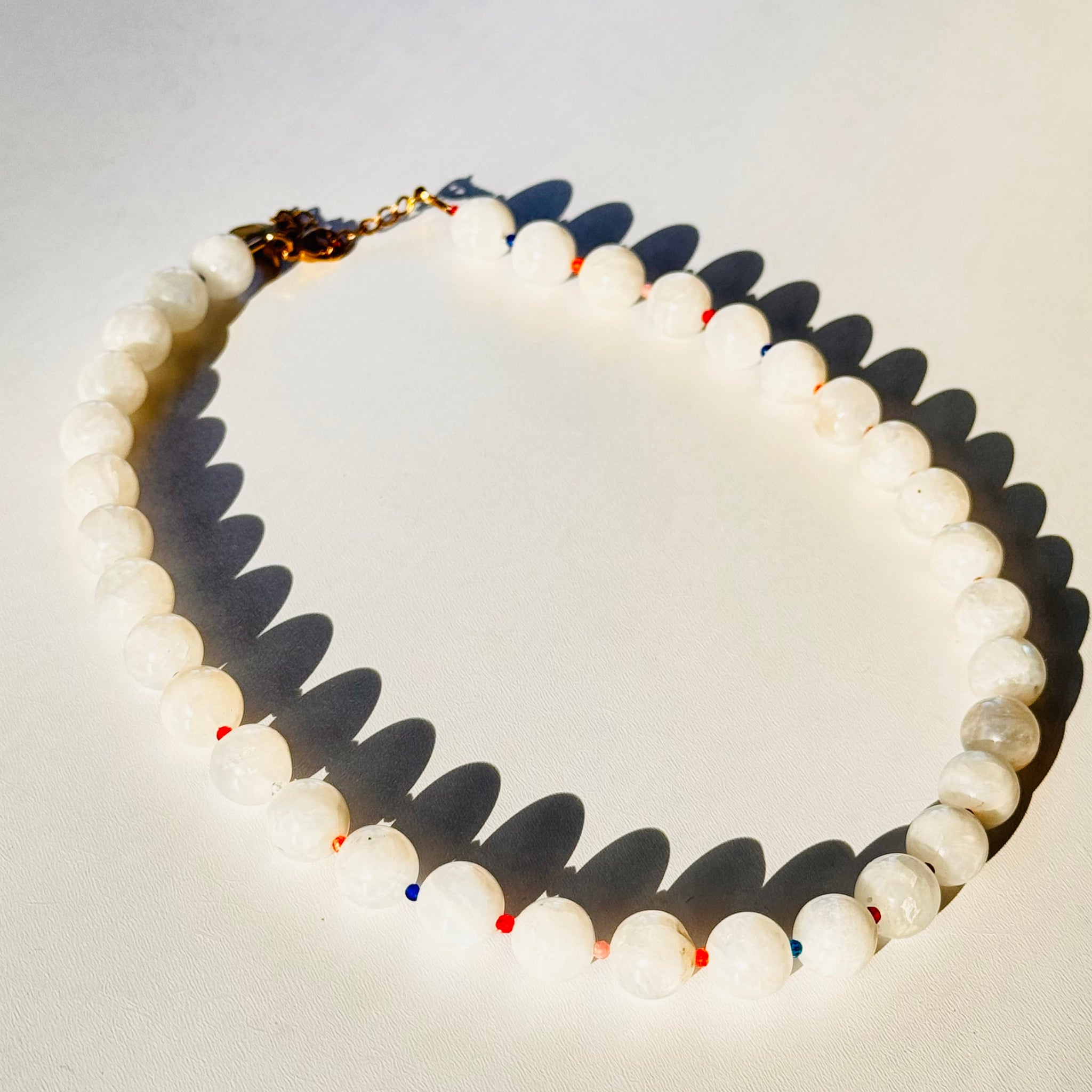 Necklace with white beads and a gold clasp on a light background