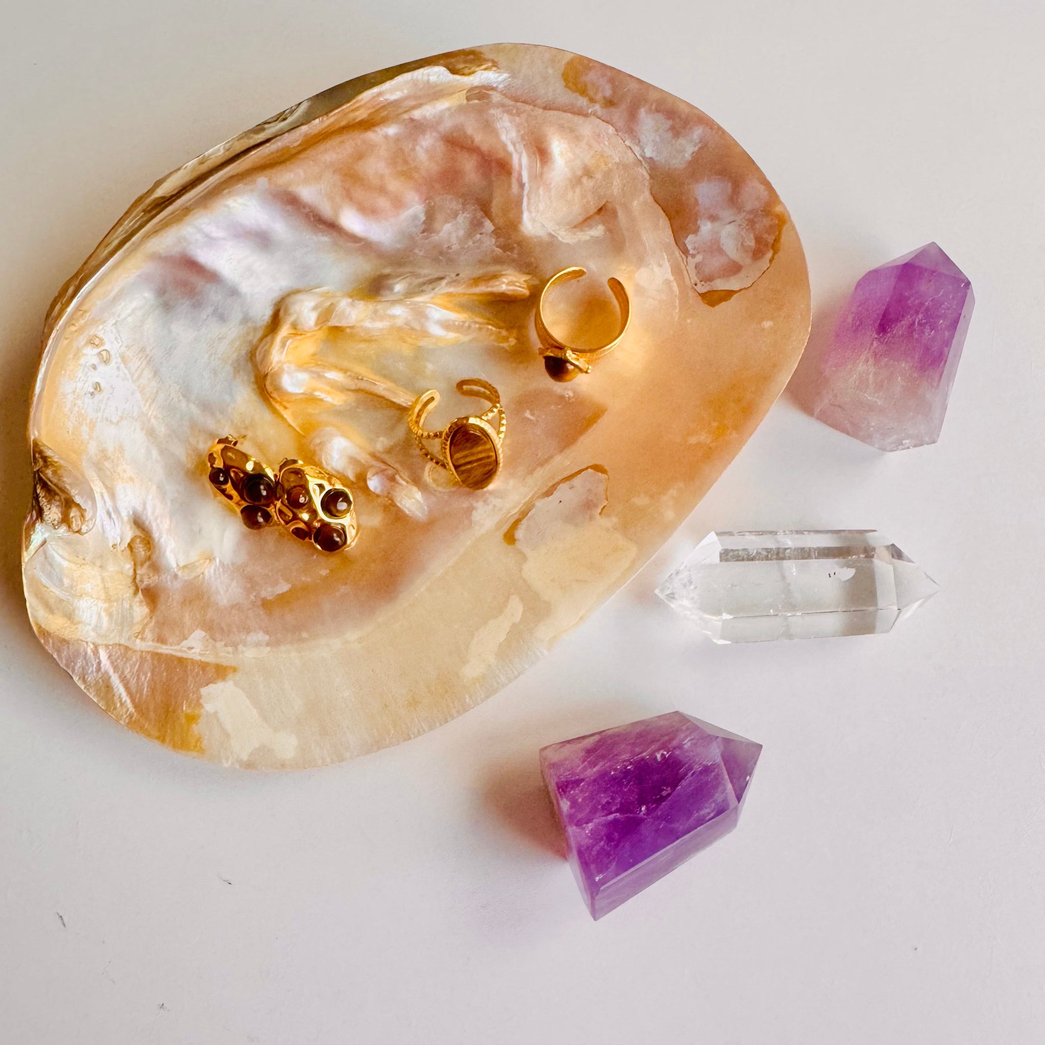 Gold jewelry on a stone with crystals on a white background