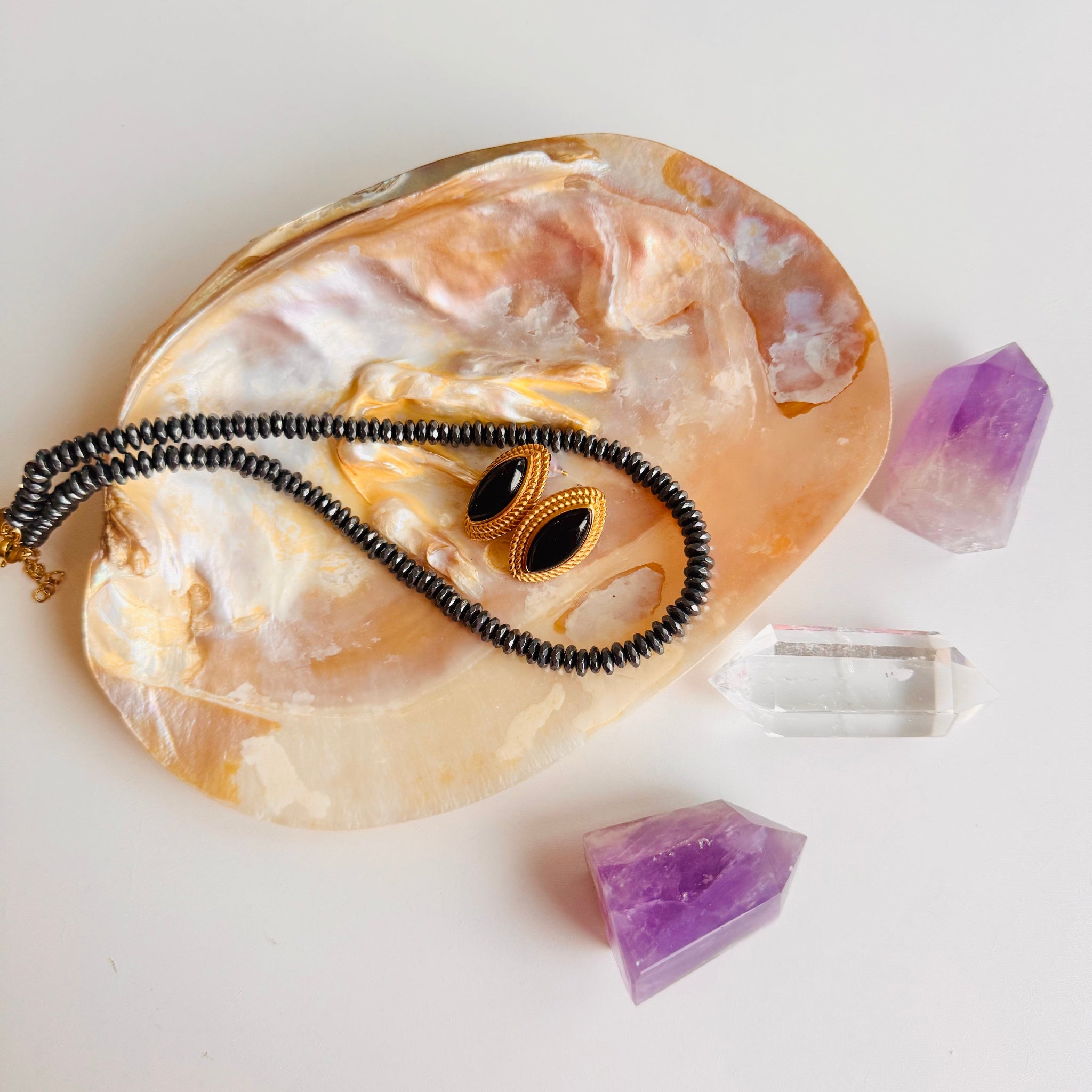 Necklace on a large stone with purple crystals and clear crystal on a white background