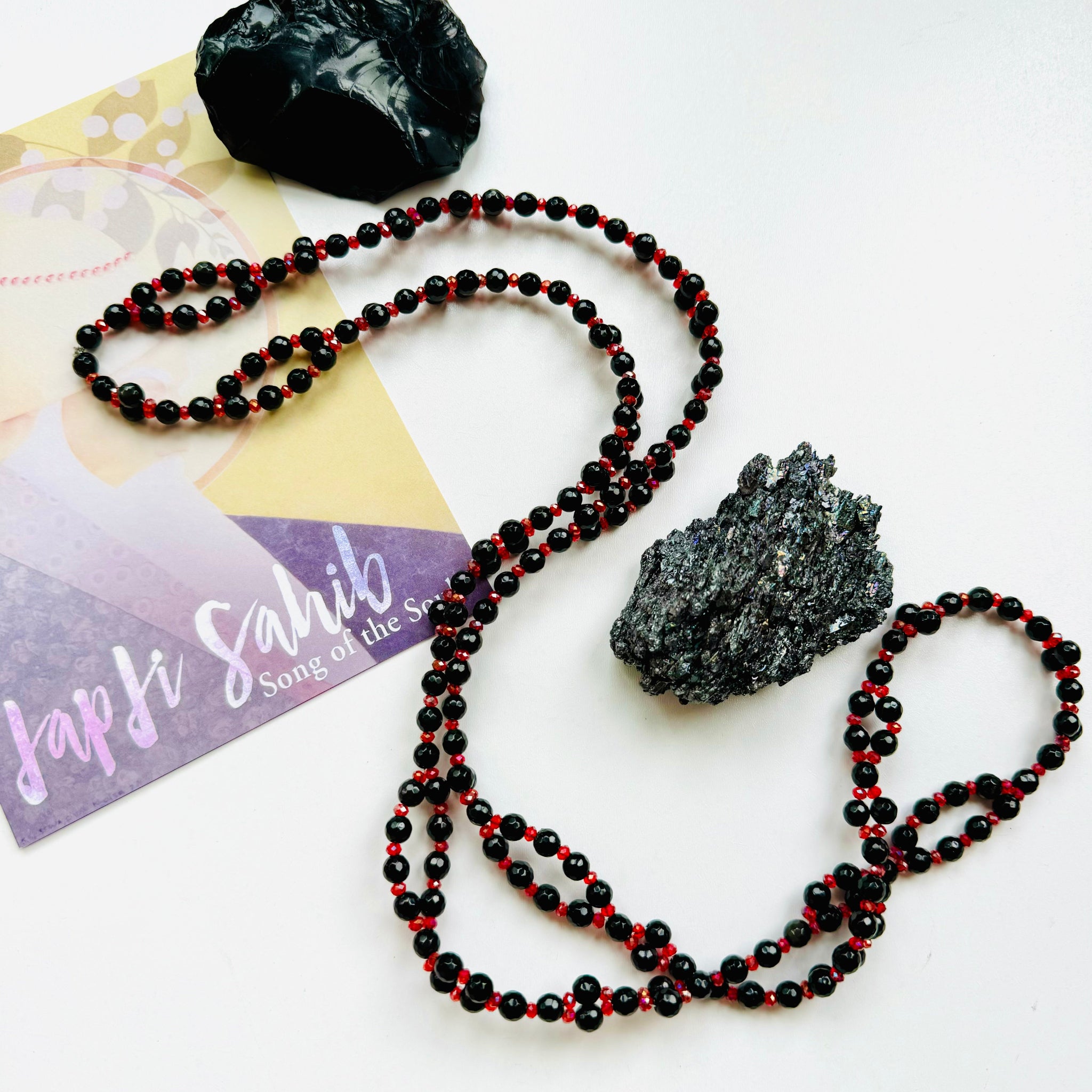 black and red beaded necklace with black crystals on white surface