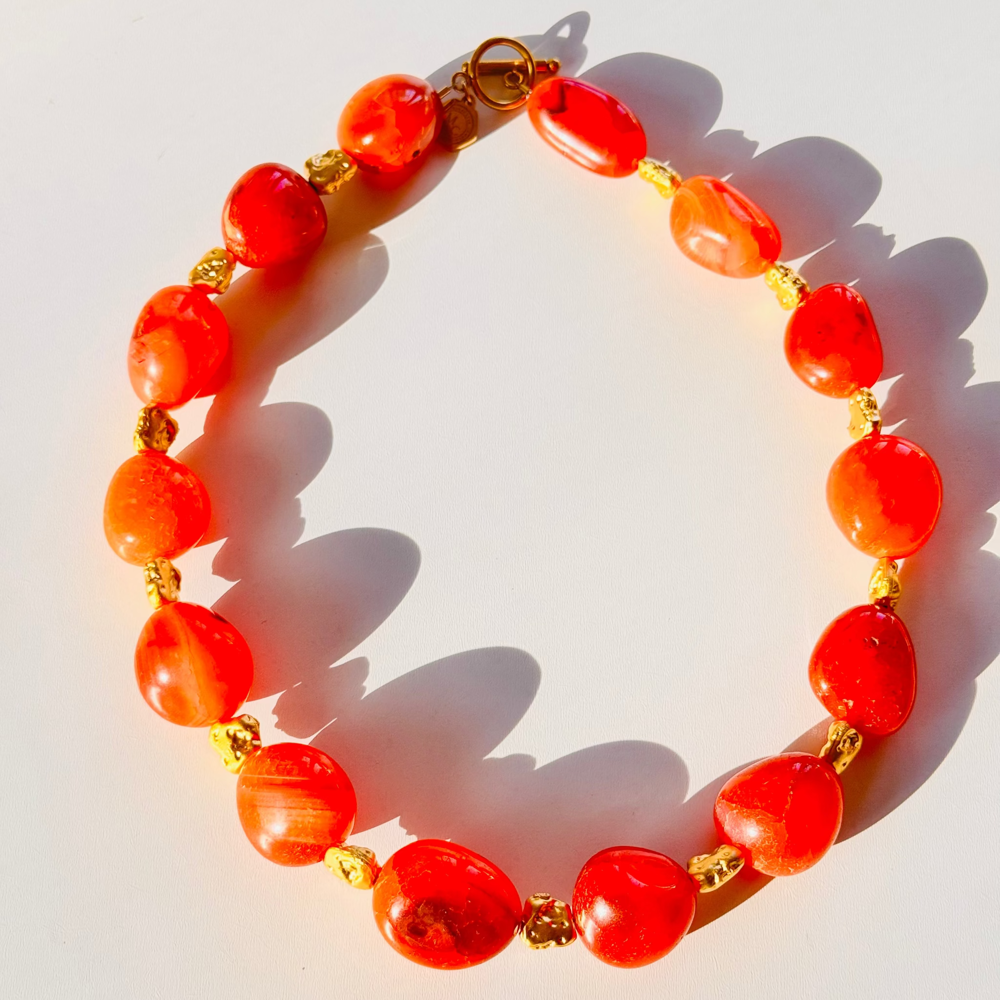 Bracelet with red beads and gold accents on a white background