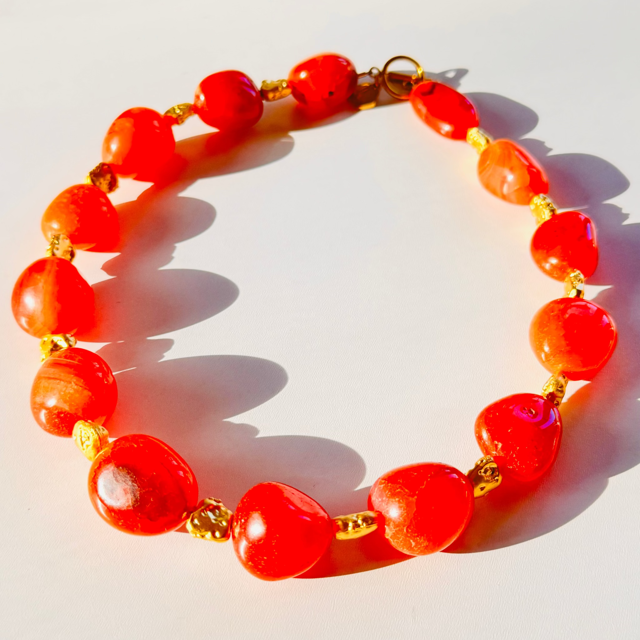 Red beaded bracelet with gold accents on a white background
