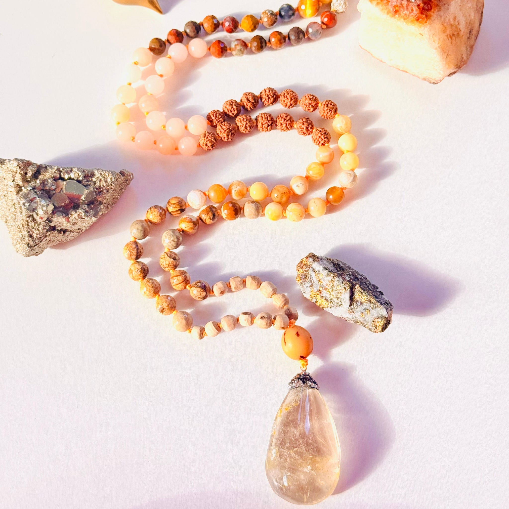 A handmade japa mala with a blend of 8mm & 10mm gemstones including yellow opal, jasper, and agate, among others, knotted and finished with a yellow beryl pendant.