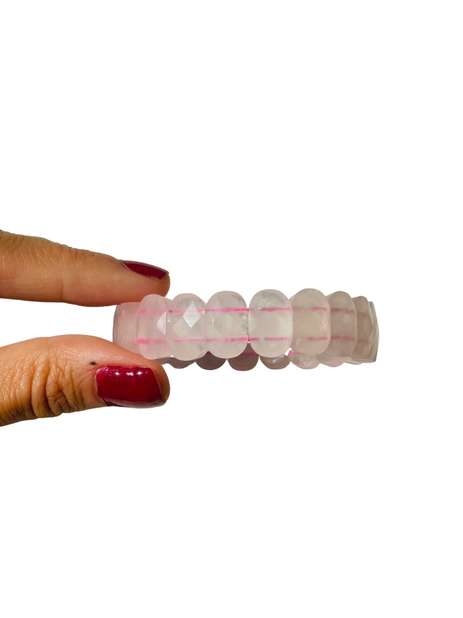 A hand holding a chunky bracelet with rose quartz stones, featuring a mix of pink and clear stones.