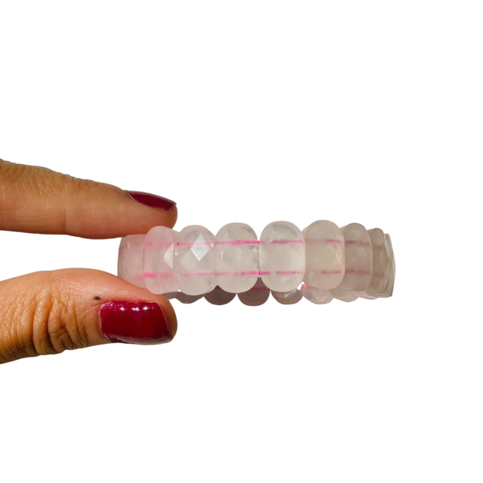 A hand holding a chunky bracelet with rose quartz stones, featuring a mix of pink and clear stones.
