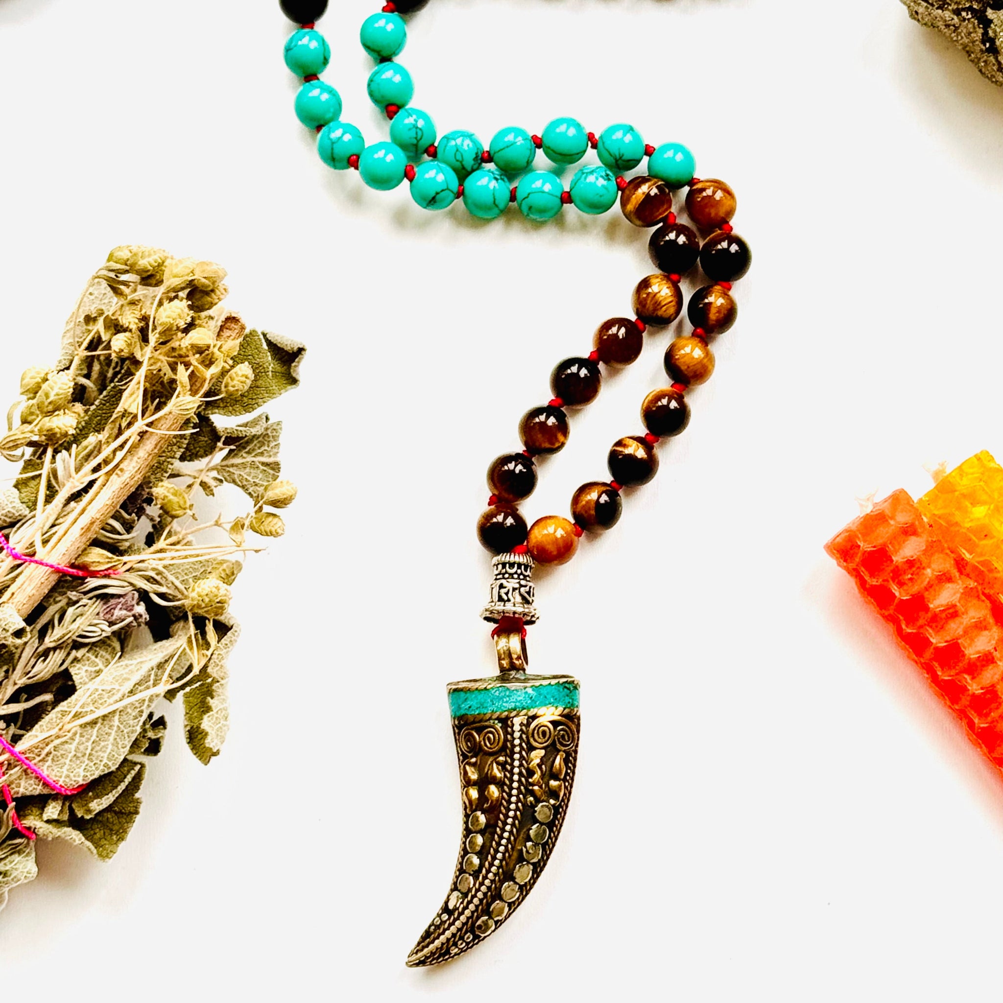 A variety of colorful gemstone beads and a Tibetan horn pendant, arranged on a white background closeup image.