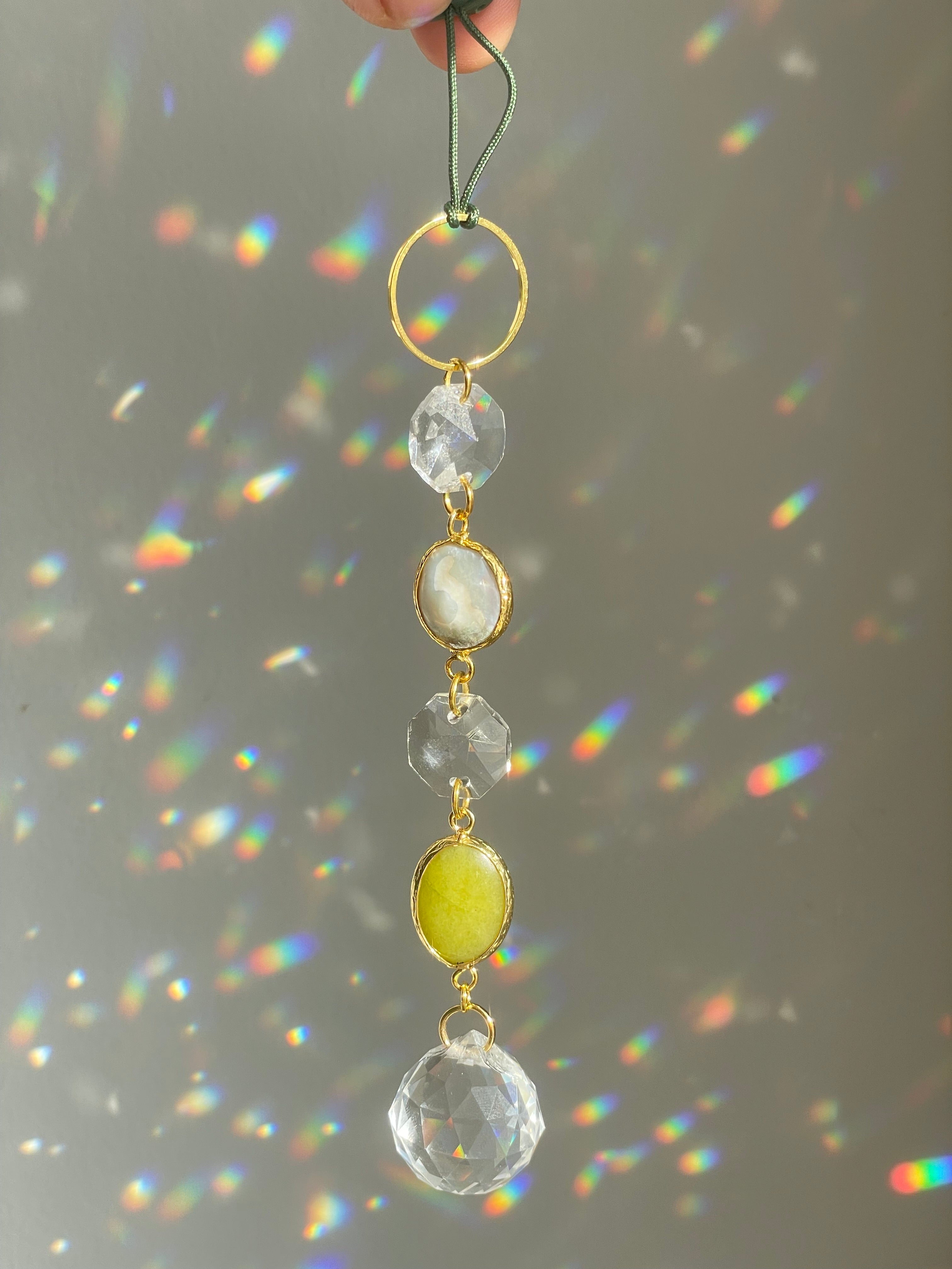 white and greent agate hanging ornament with crystal prism in front of white surface