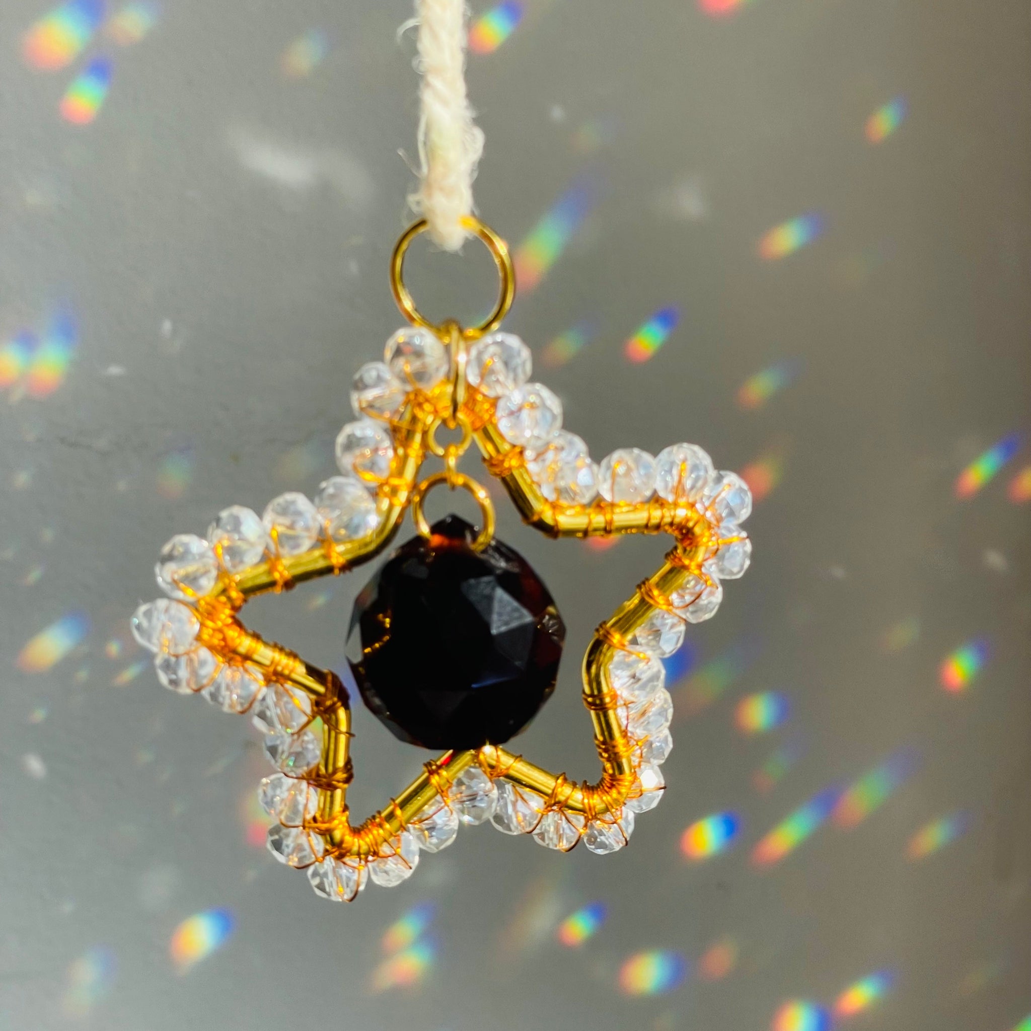 Star-shaped pendant with a black bead and clear beads on a gray background