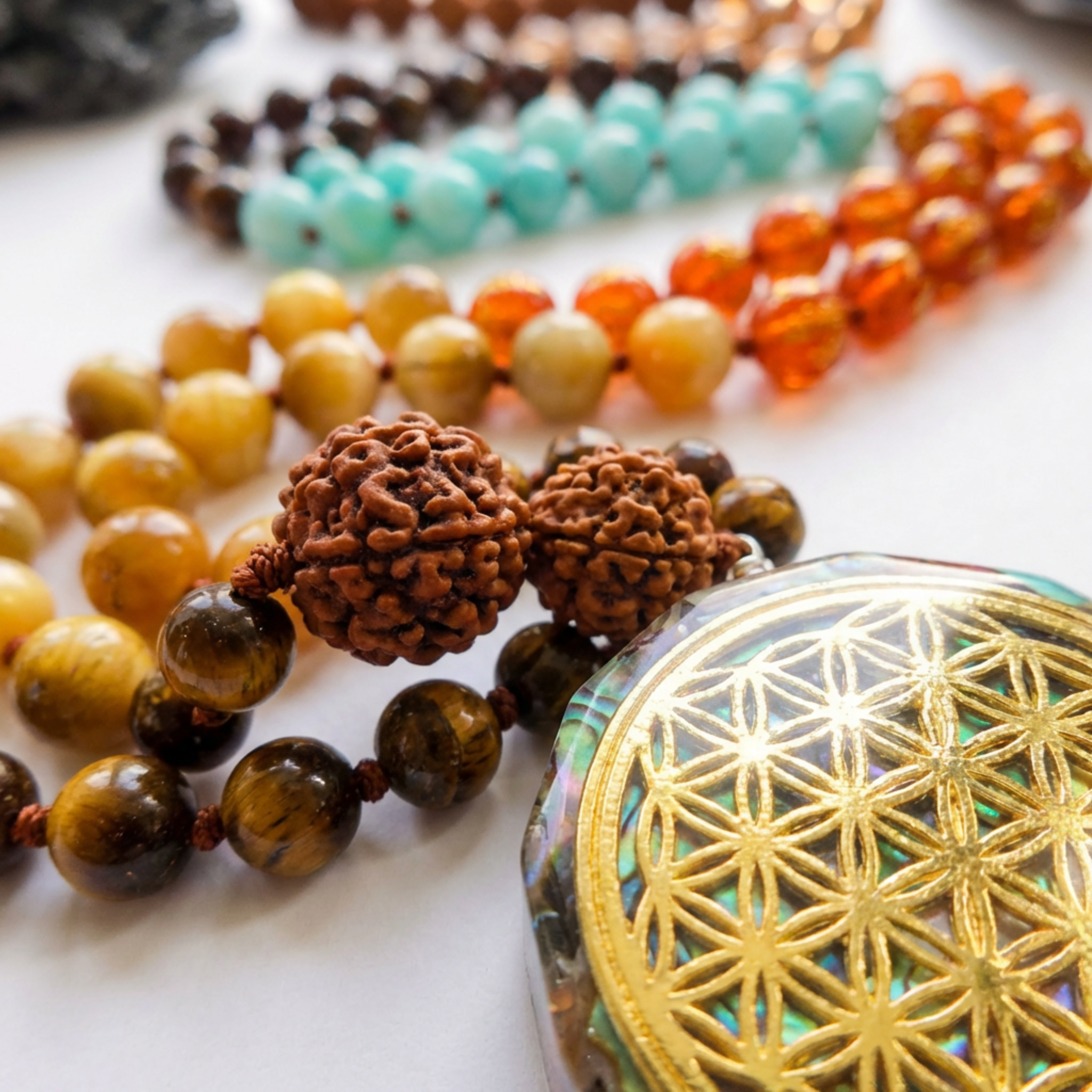 Colorful beaded necklaces with a gold and multicolor pendant on a light background