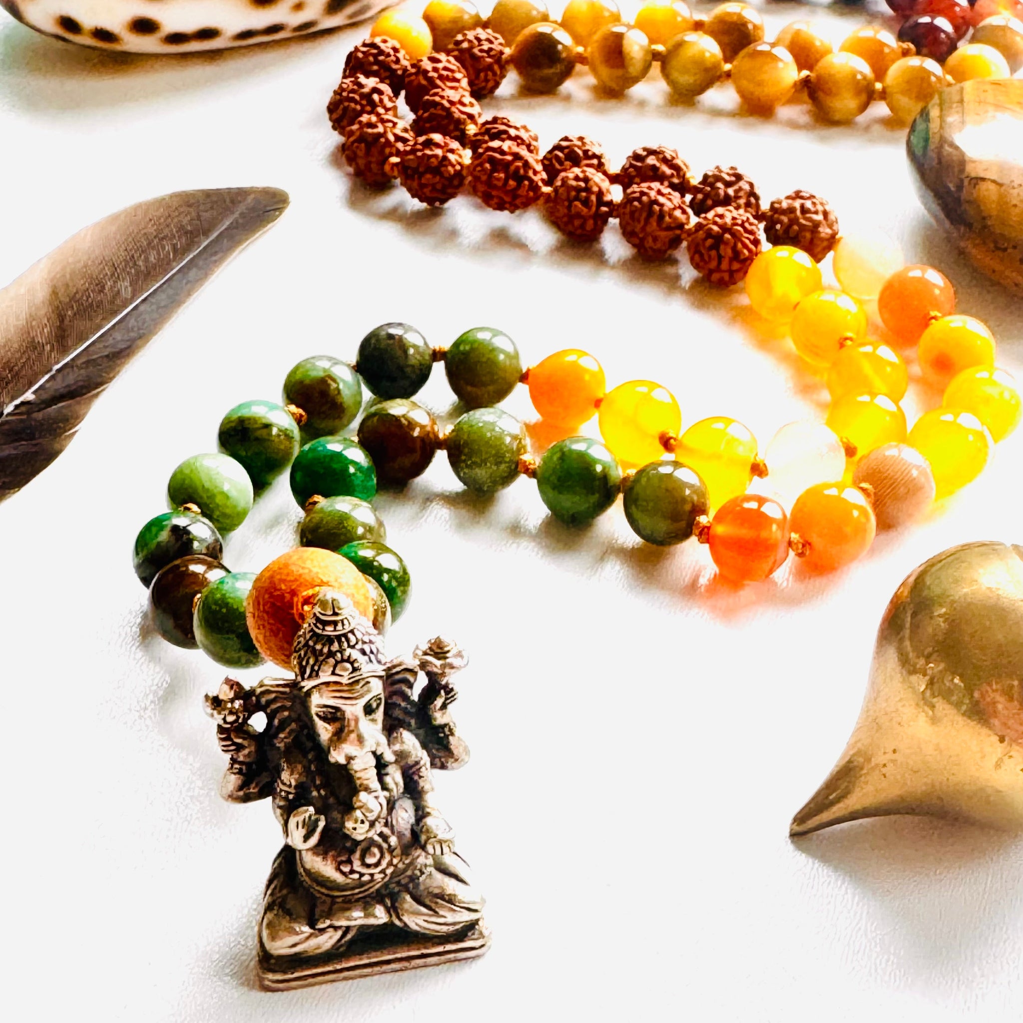 Colorful beaded bracelets with a deity pendant on a white surface