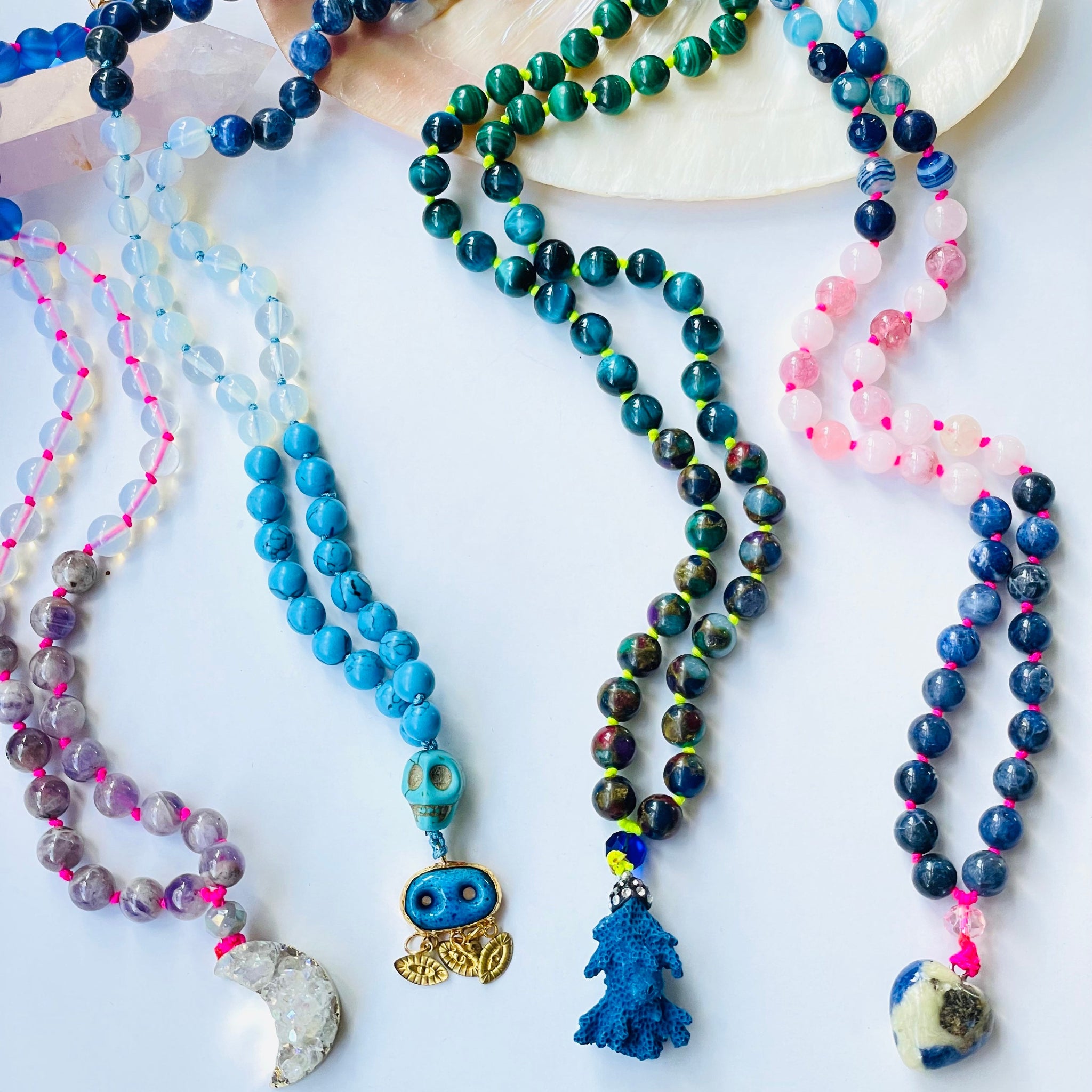 Colorful beaded necklaces on white background with different pendants