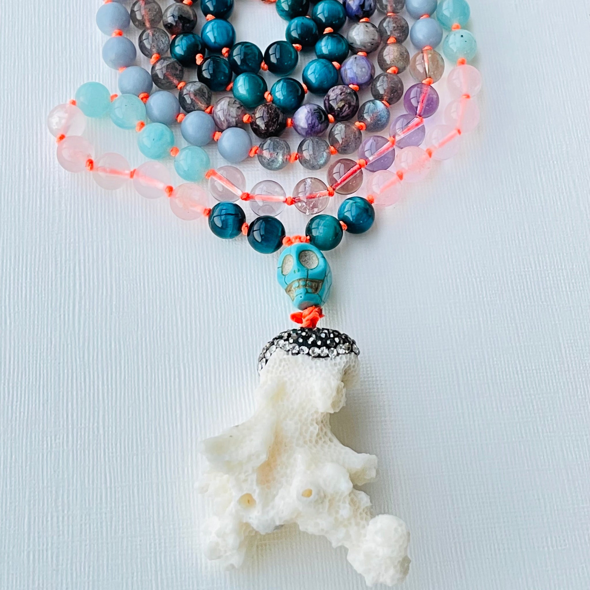 Beaded blue, purple and white gemstones with coral pendant
