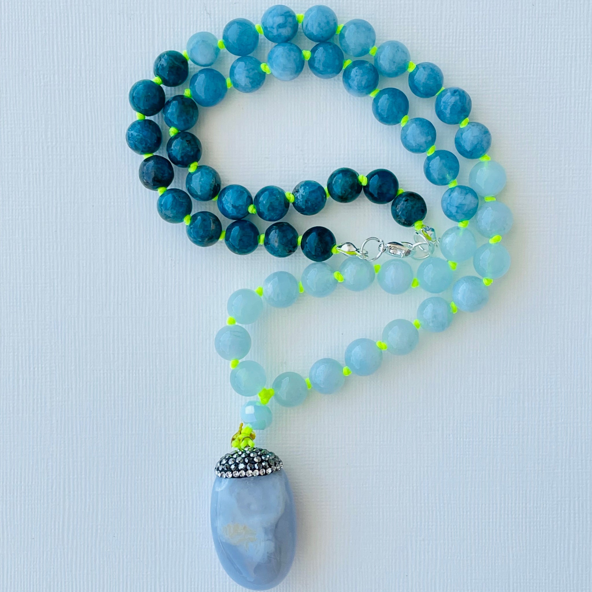 beaded blue gemstones on bright yellow string with a blue gem pendant