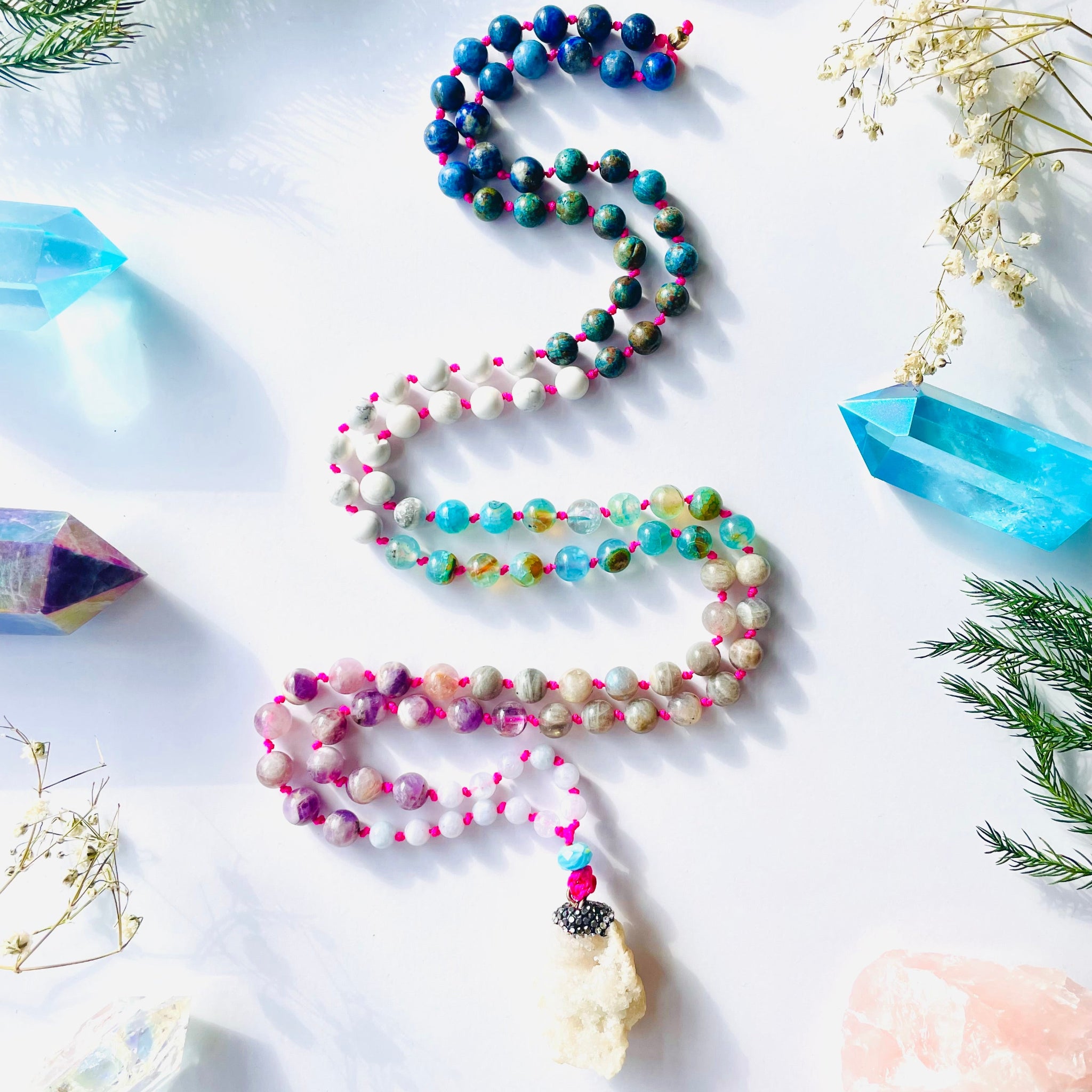 colorful gems beaded with geode pendant on white surface with blue and purple crystals and flowers