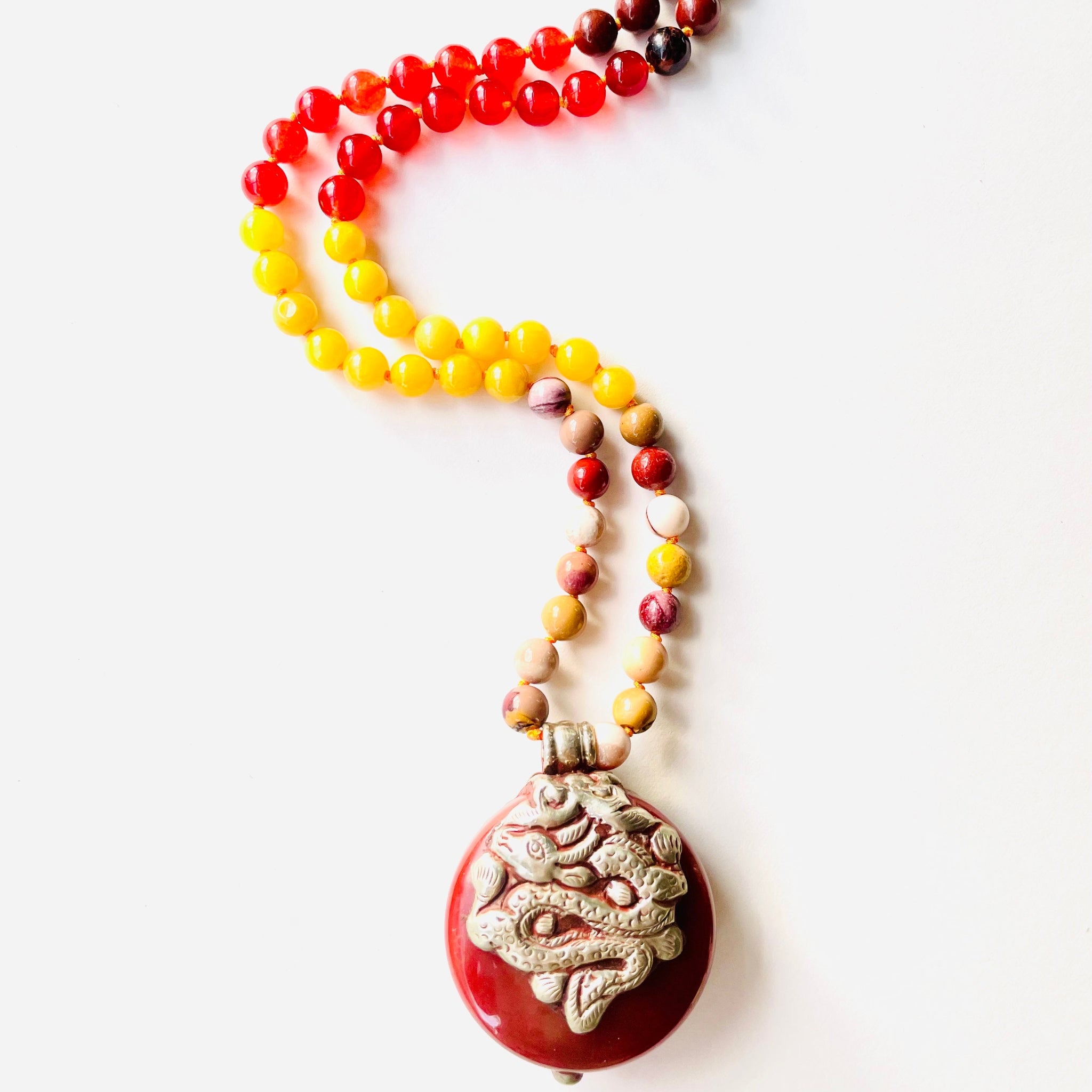 Colorful beaded necklace with a decorative pendant on a white background