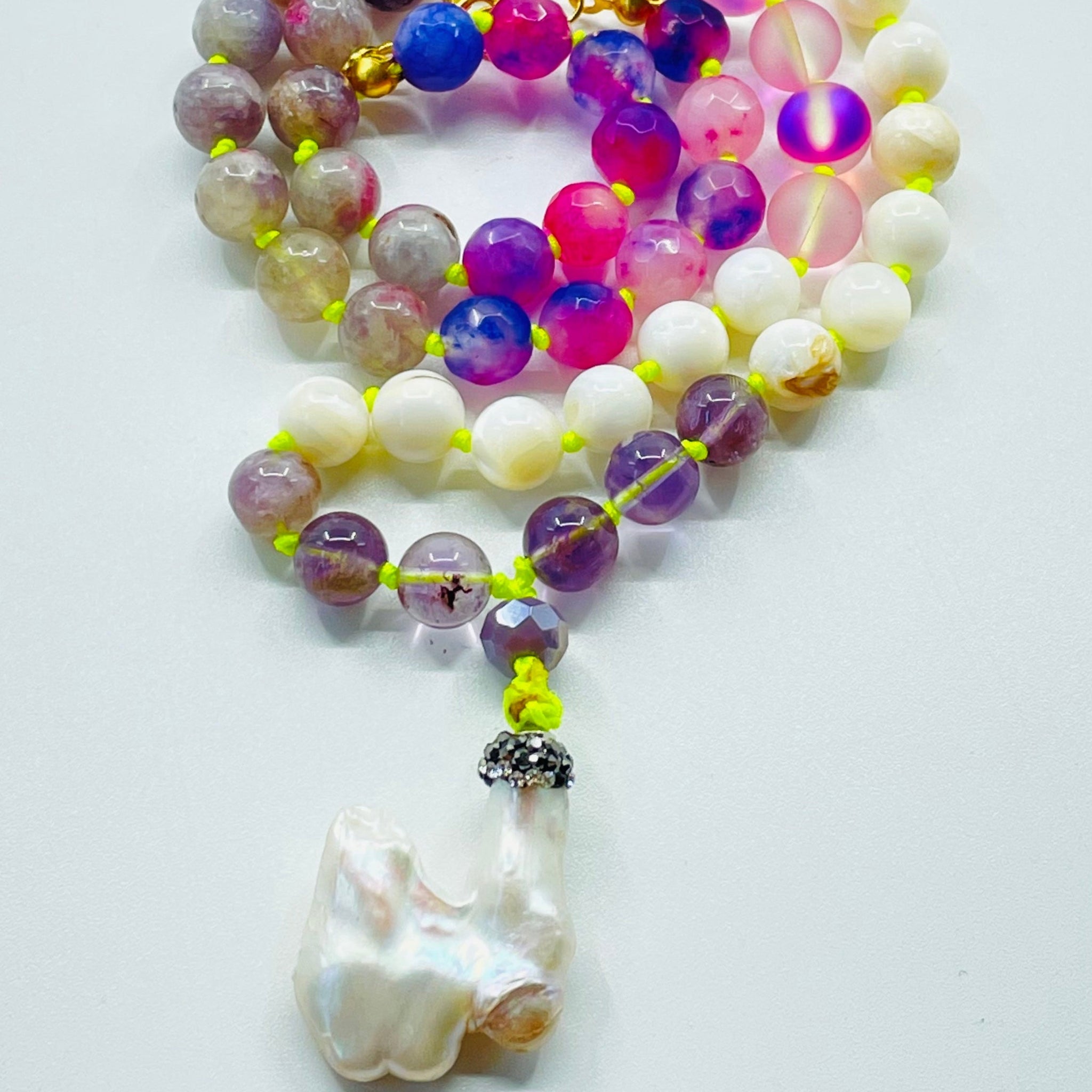 beaded white and pink gemstones with pearl pendant on white surface