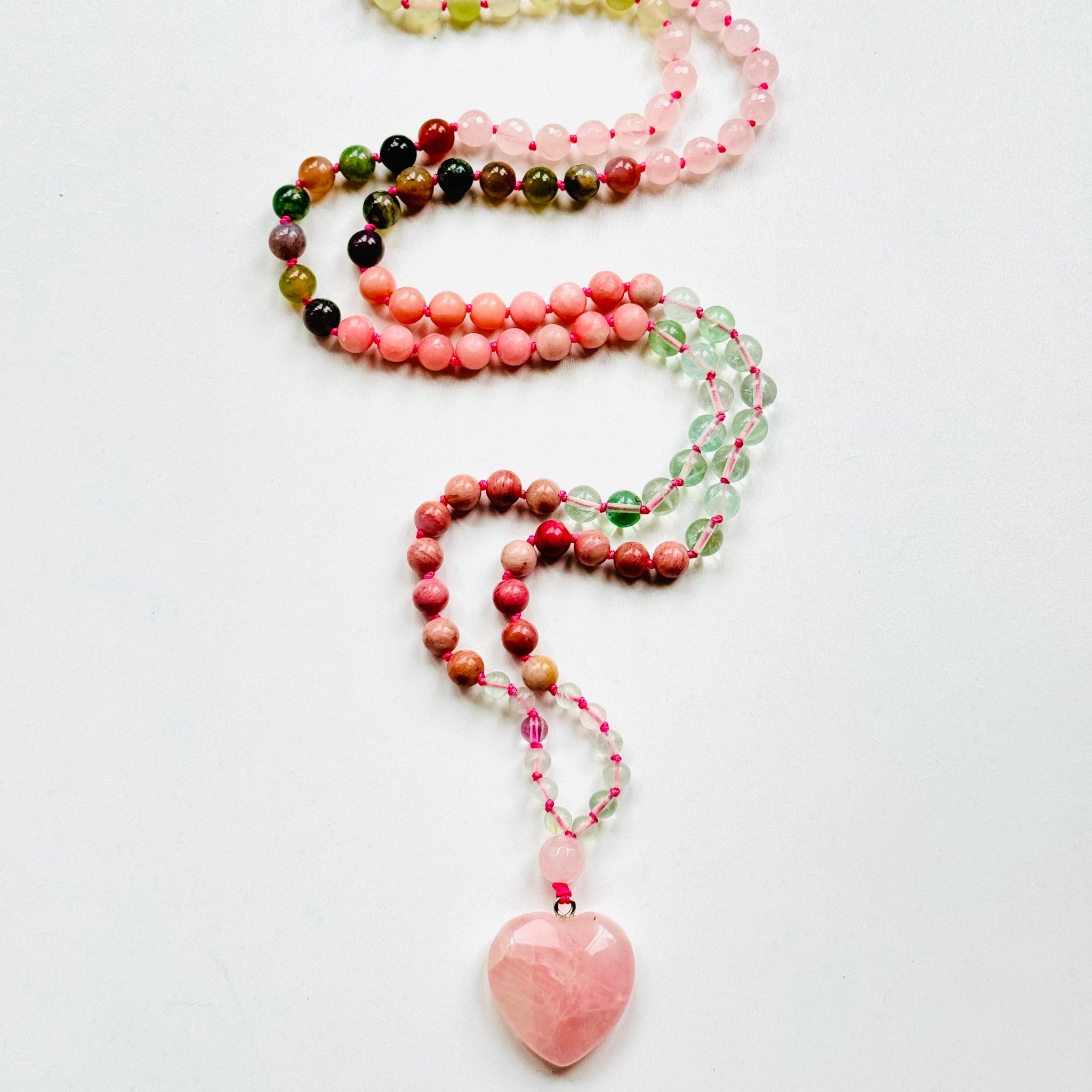Anahata pink mala with gemstones on white surface