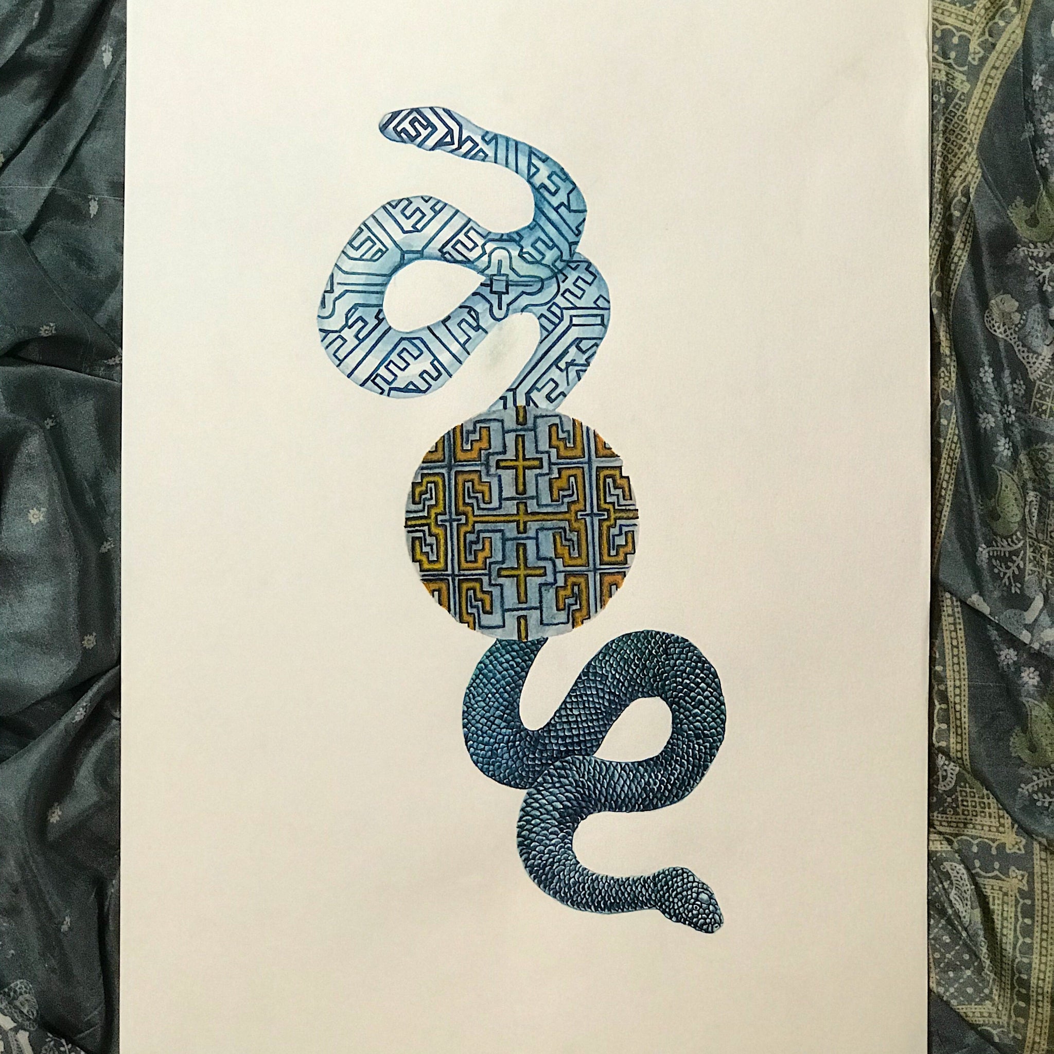 Decorative book with geometric snake design on a textured fabric background