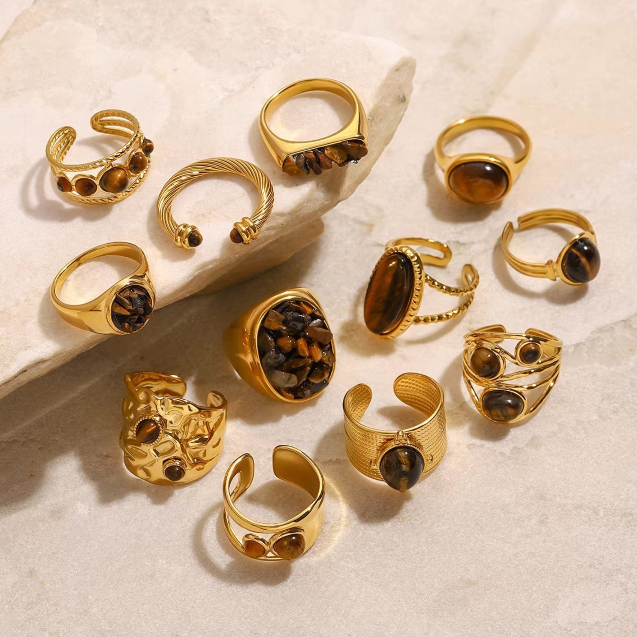 Collection of gold rings with gemstones on a textured surface