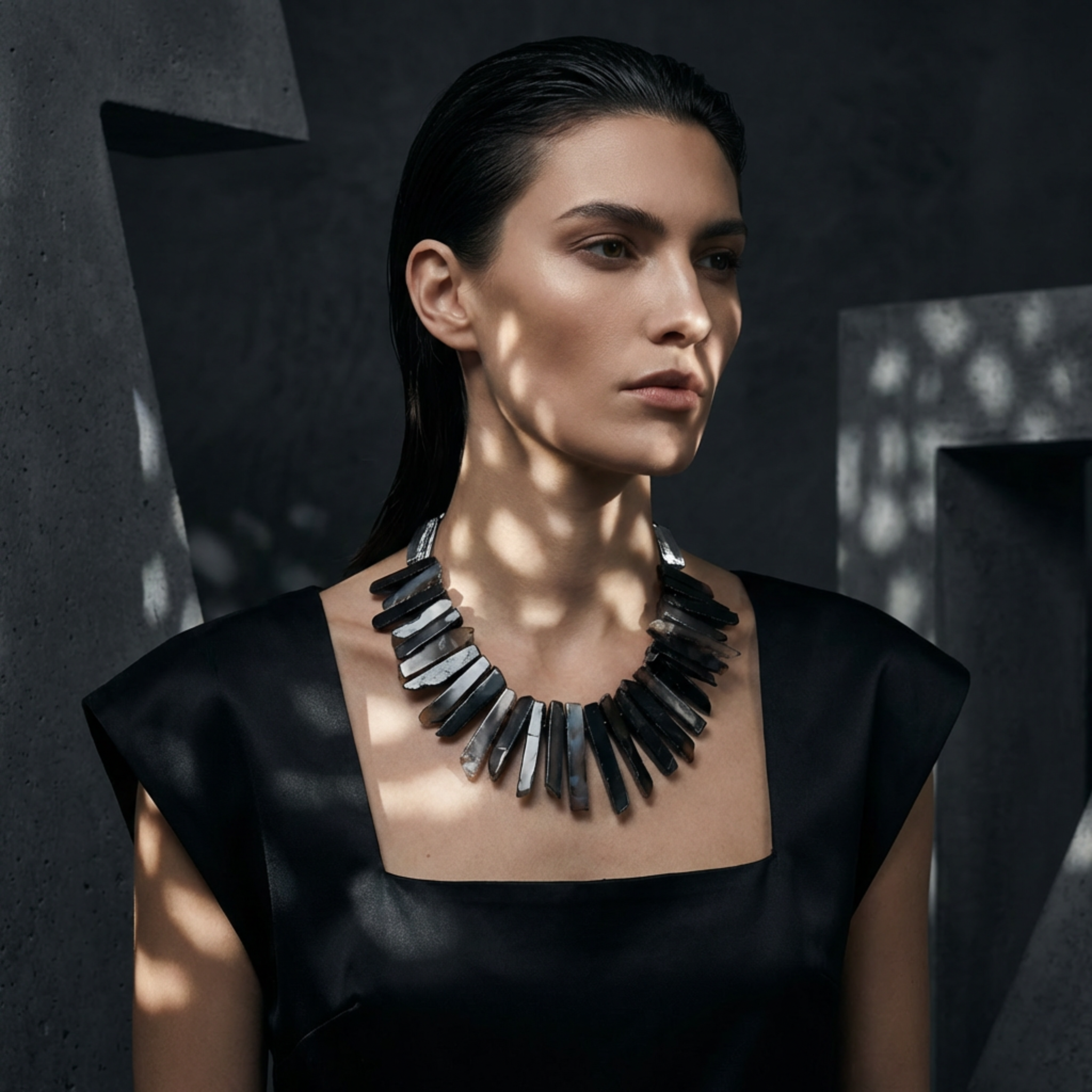 Woman wearing a black and silver necklace against a dark background