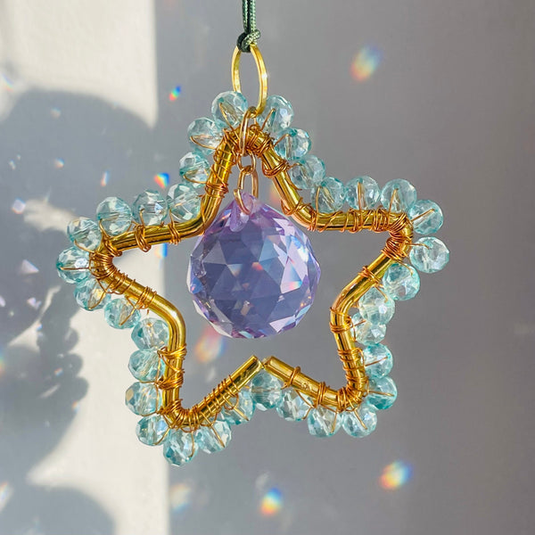 A mini star-shaped suncatcher with a central purple crystal and gold-tone metal frame, surrounded by clear crystals and a green chain for hanging.
