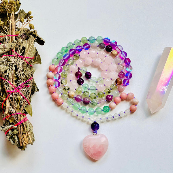 Pink and green beaded gemstone necklace with pink heart pendant and sage and a pink crystal next to it