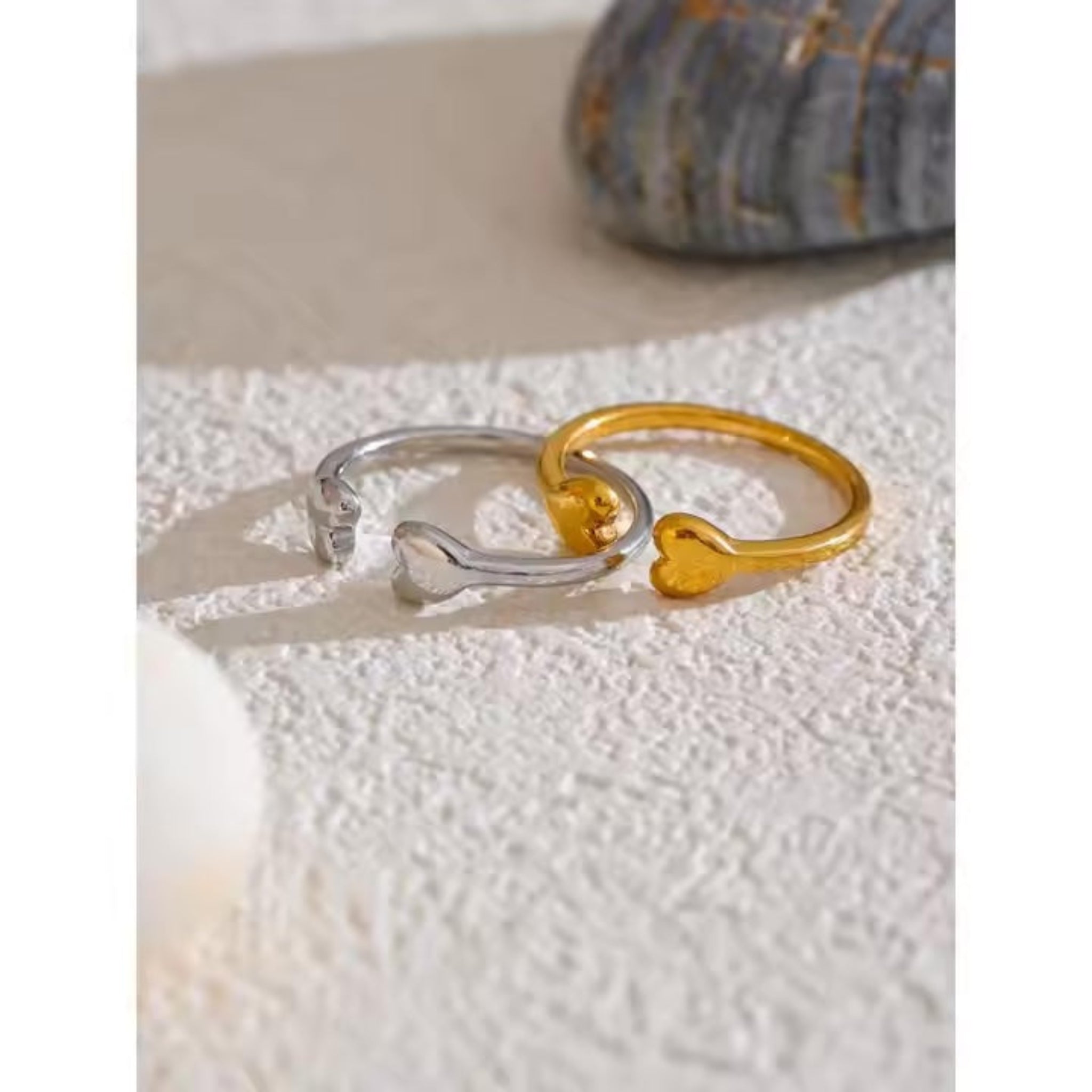 Two heart-shaped rings on a textured surface.