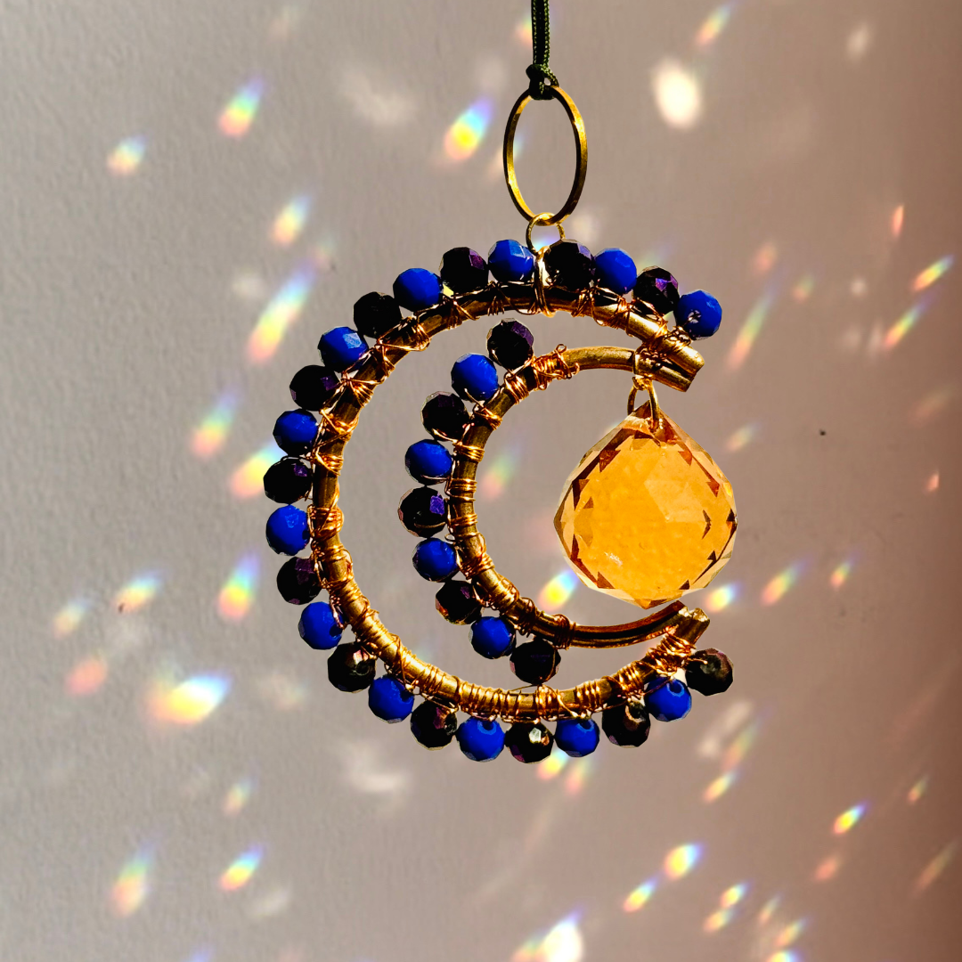 Decorative hanging ornament with blue and black beads and a yellow teardrop pendant on a plain background.