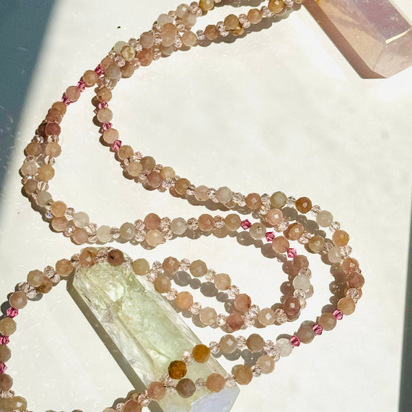 pink beaded gemstone necklace with crystals on white surface
