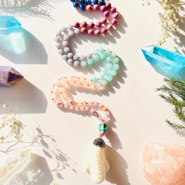 Colorful beaded bracelets on a light surface with crystals and plants