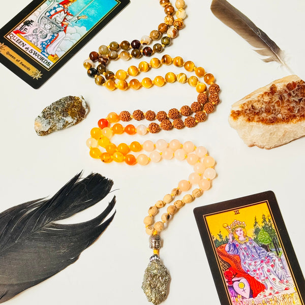 Meditative objects including tarot cards, beads, and crystals on a white surface