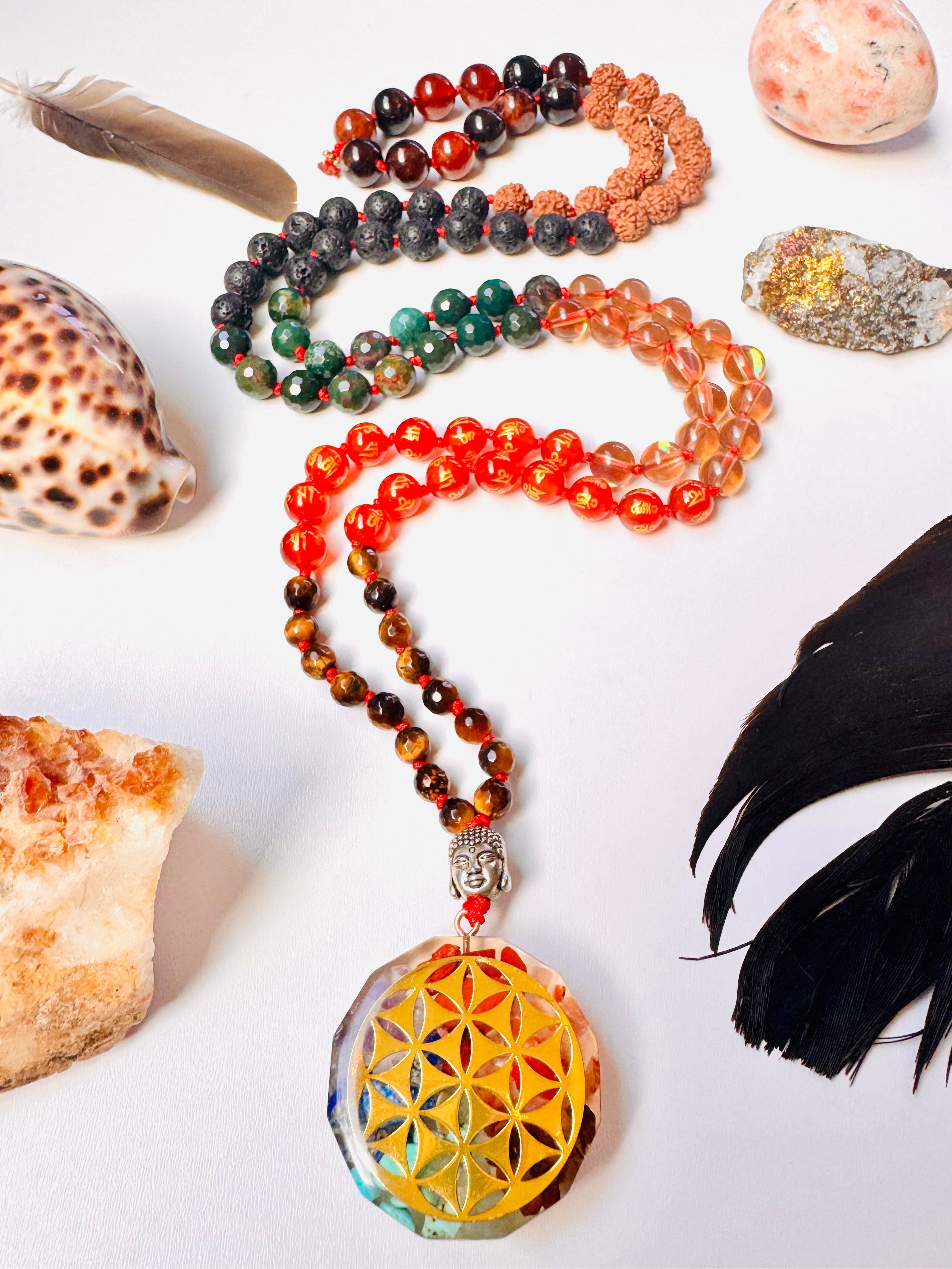 Colorful beaded necklace with a yellow crystal pendant on a white surface with shells and feathers.