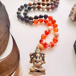 Beaded bracelets with a small Ganesha statue on a white surface