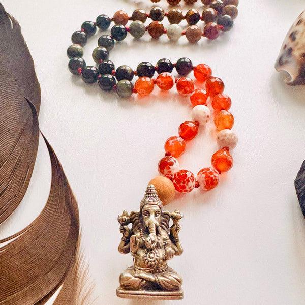 Beaded bracelets with a small Ganesha statue on a white surface