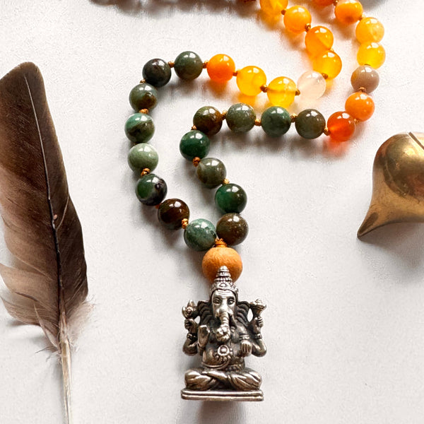 Beaded necklaces with different types of beads on a white surface, accompanied by a feather.