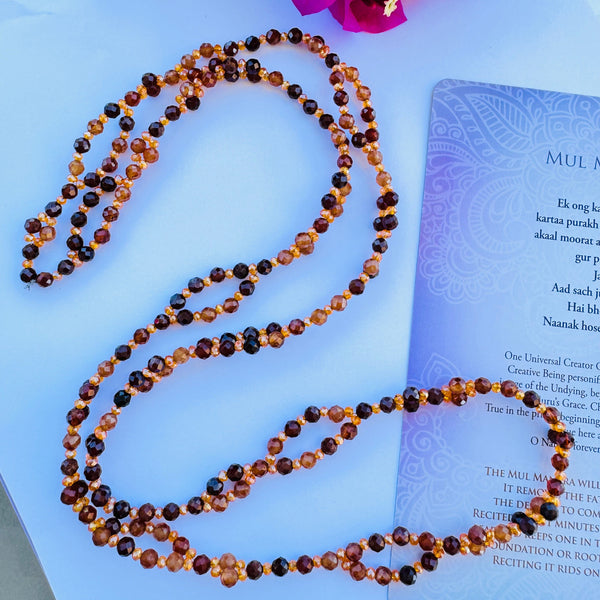 Beaded Brown and orange gemstone tantric necklace decorated with mantra card on white surface