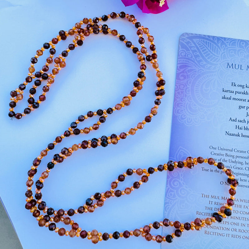 Beaded Brown and orange gemstone tantric necklace decorated with mantra card on white surface