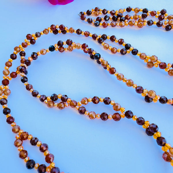 Beaded brown and orange gemstone tantric necklace on white surface