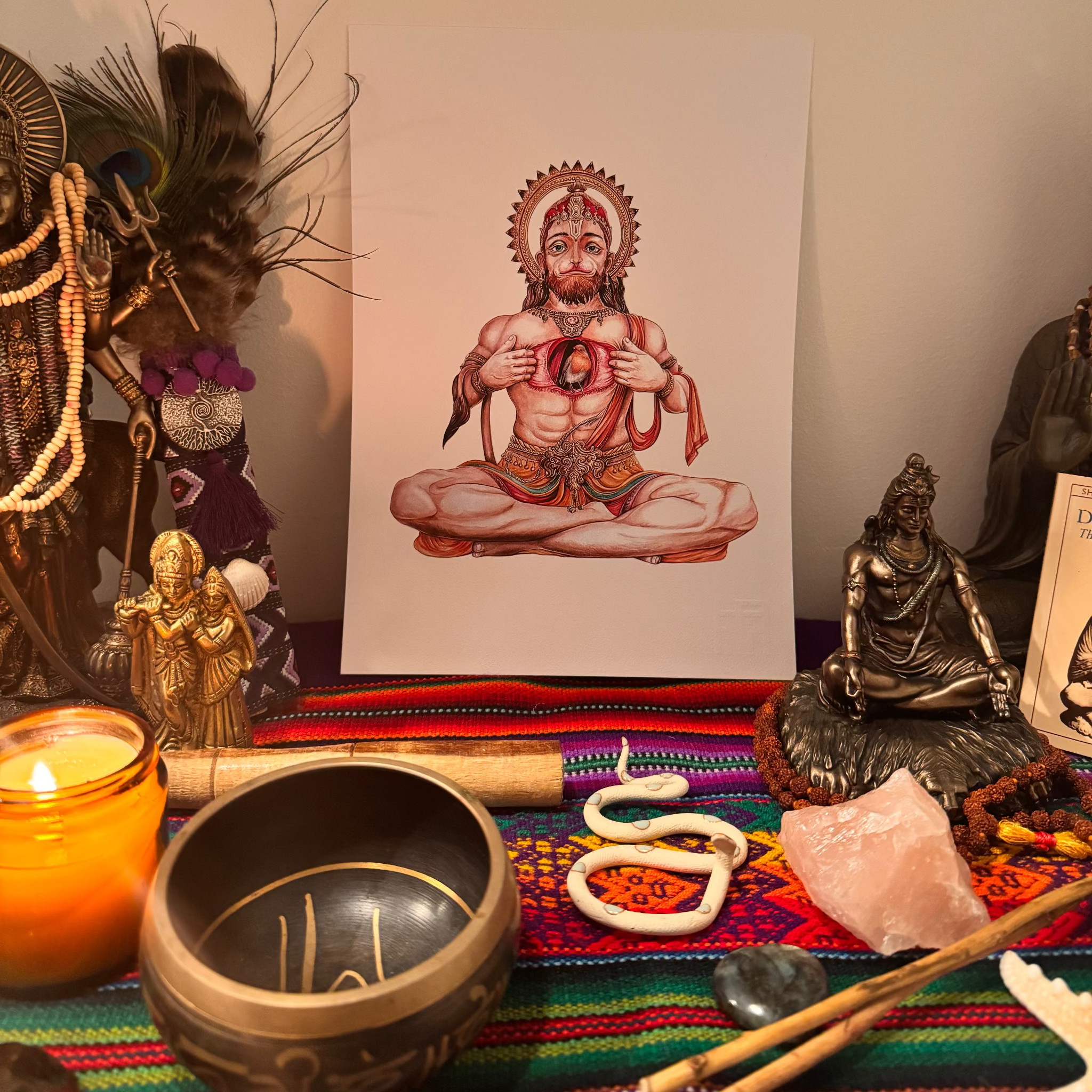Altar setup with religious statues, a bowl, and a candle on a colorful cloth.